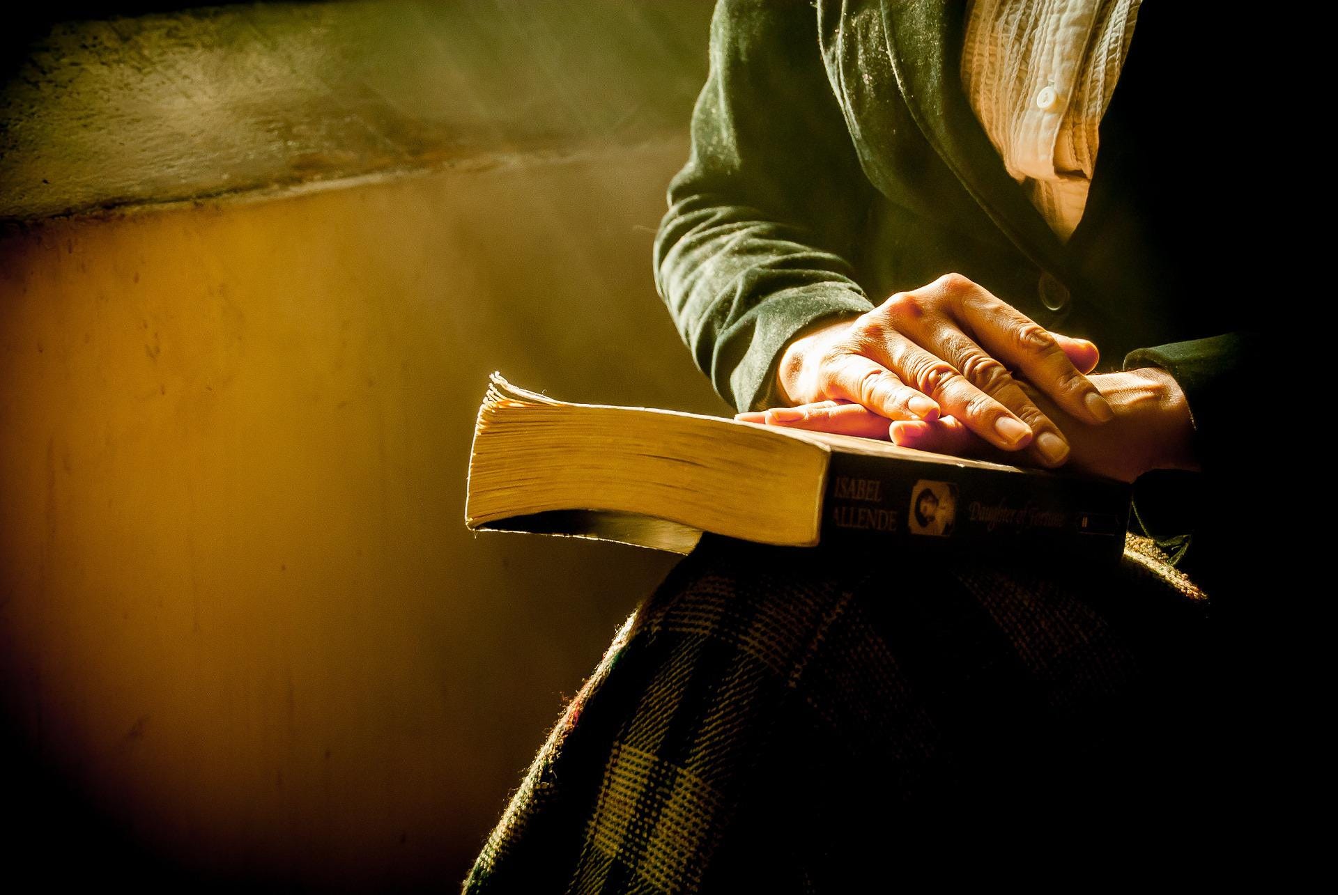 A praying woman with hands on the Bible on her lap