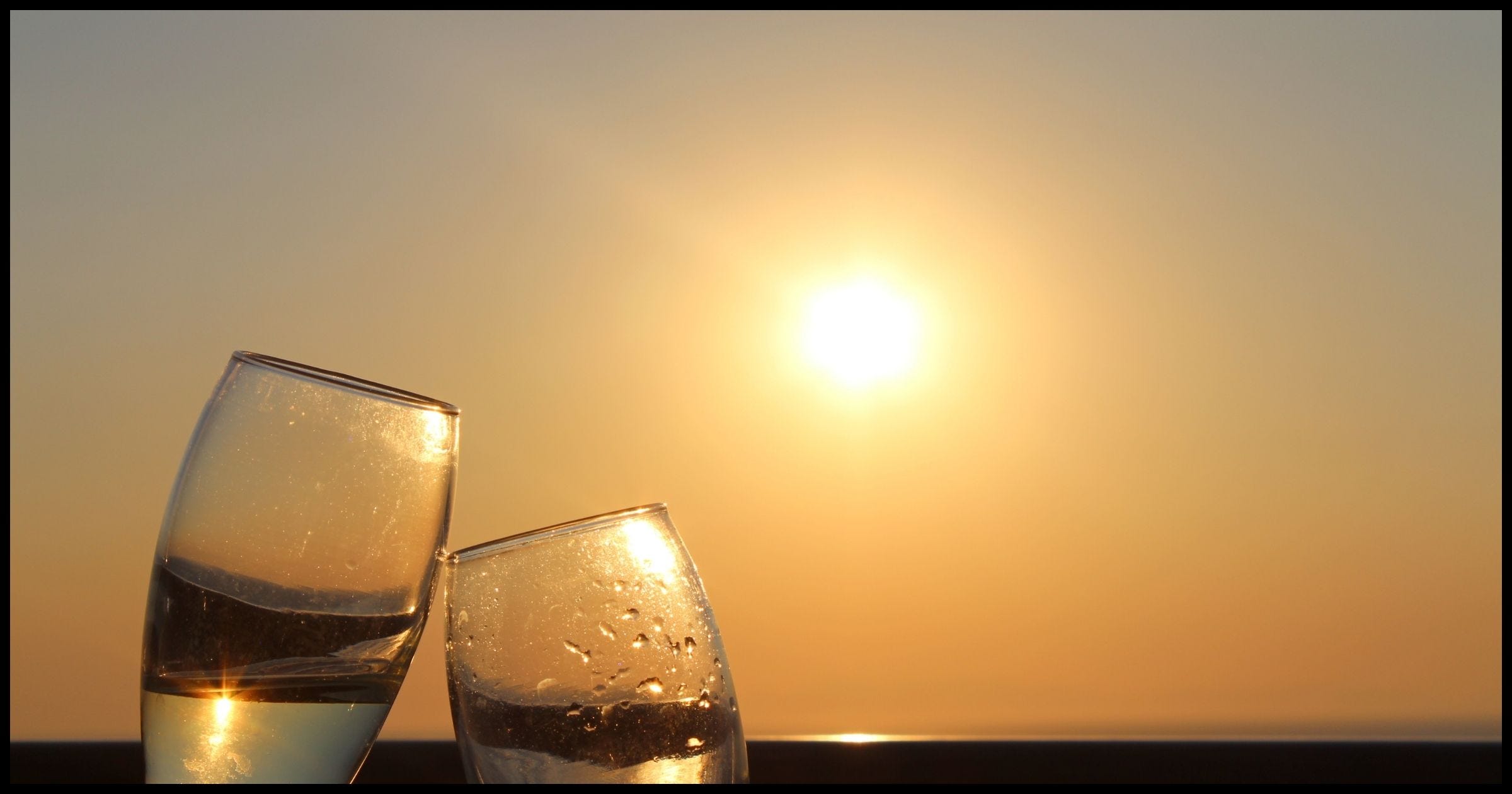 Toasting glasses in front of a sunset.