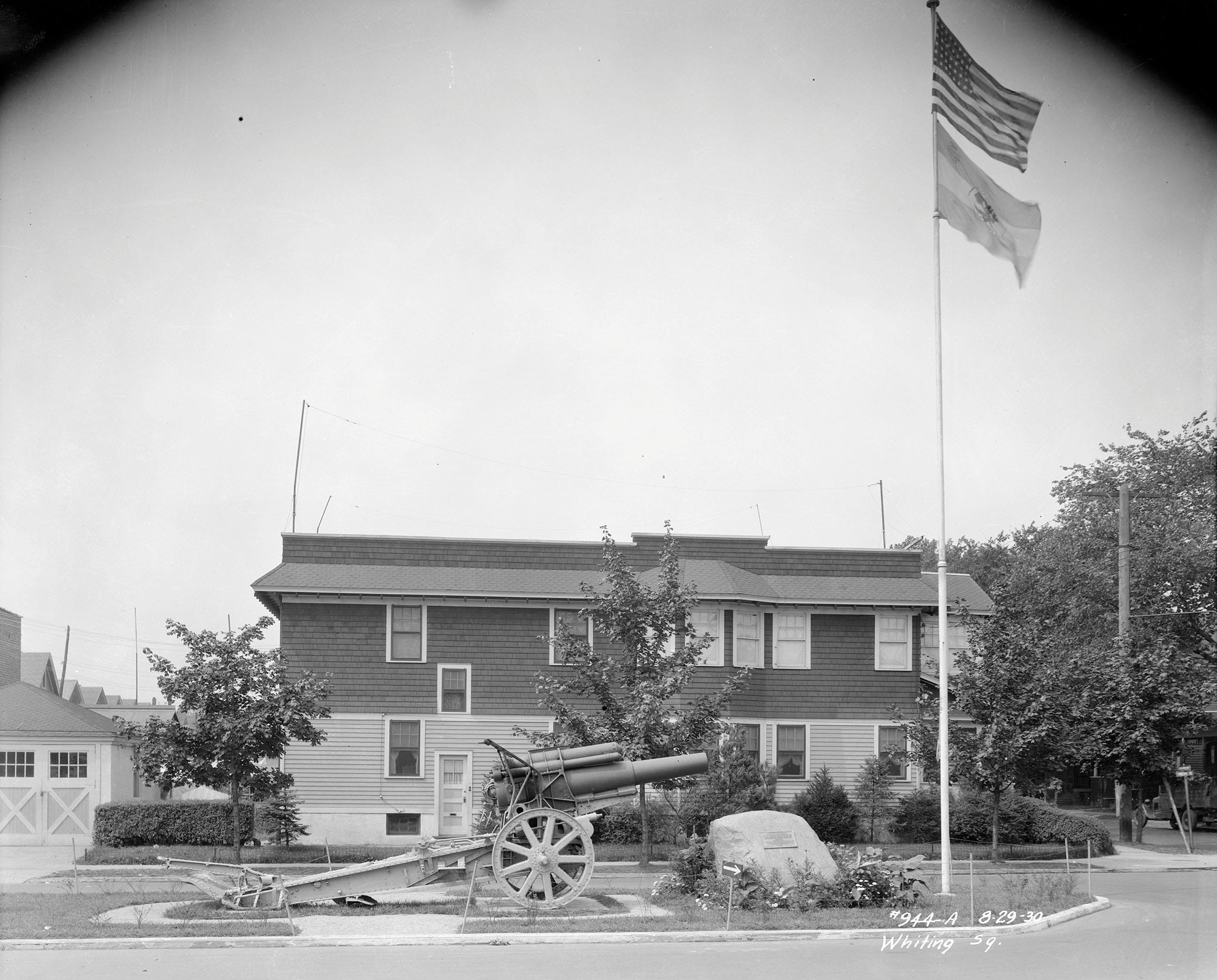 Image is a photograph of Whiting Square in 1930 with the Krupp howitzer, the rock with brass plaque on it and flagpole with flag.
