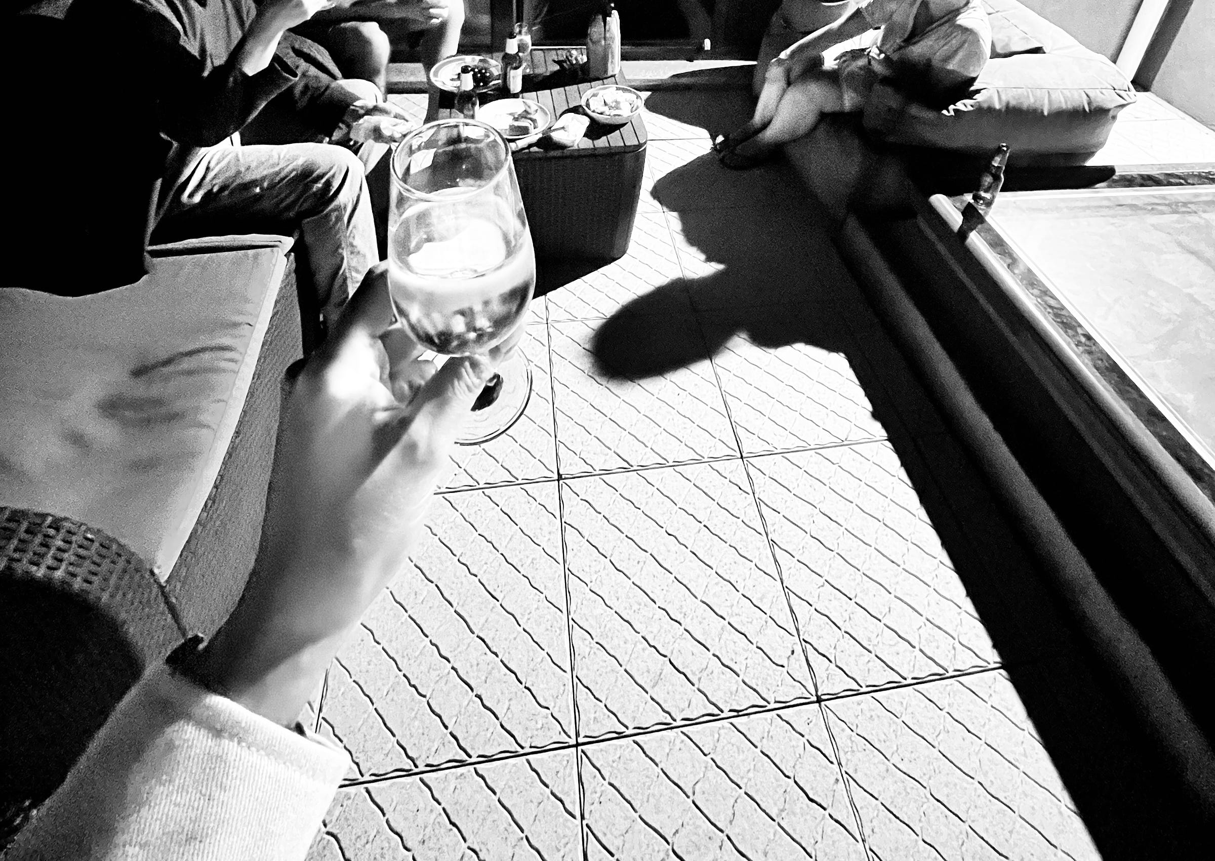 Image: black and white photo of four friends hanging out at night outside of their house. In the foreground, I'm holding a glass of Vinho Verde 