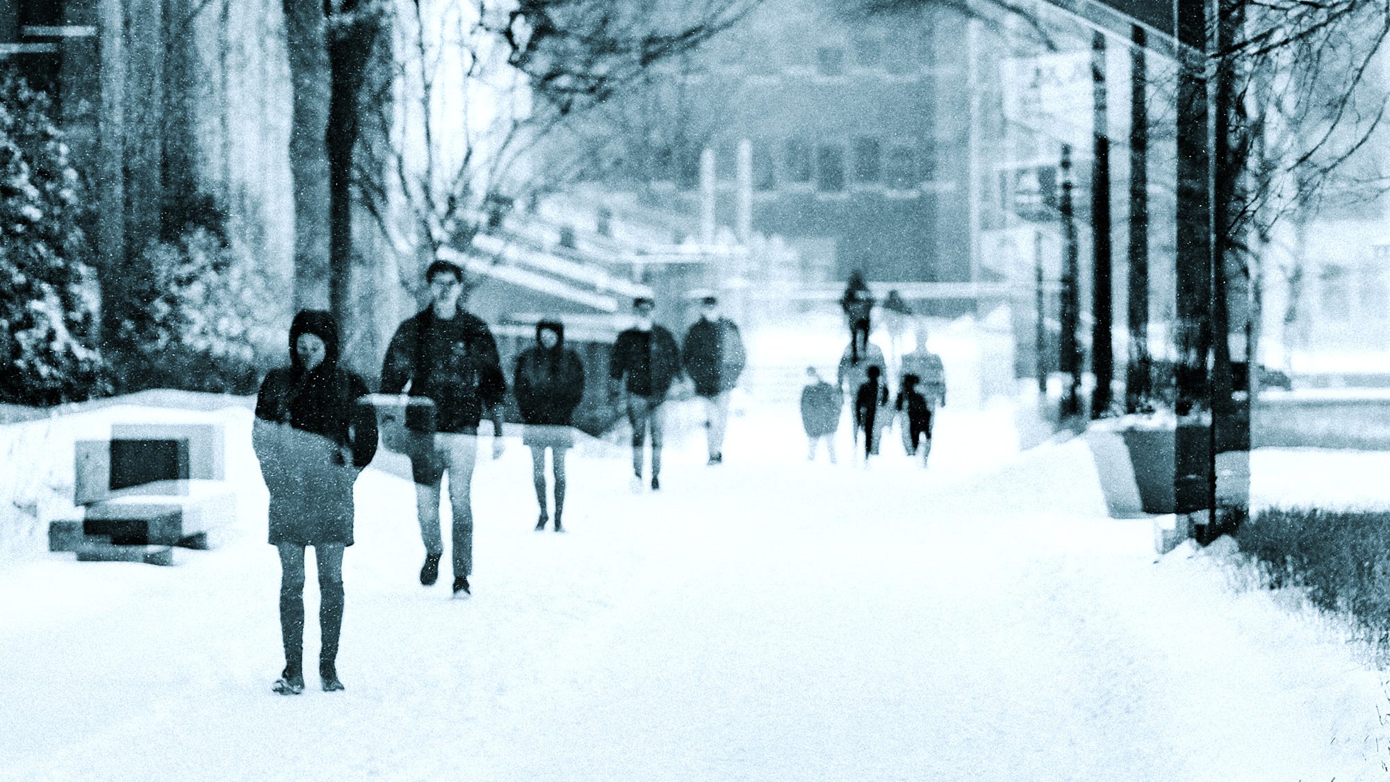 Students walk through the quad on the university campus. A double exposure photograph gives a sense of time passing by.