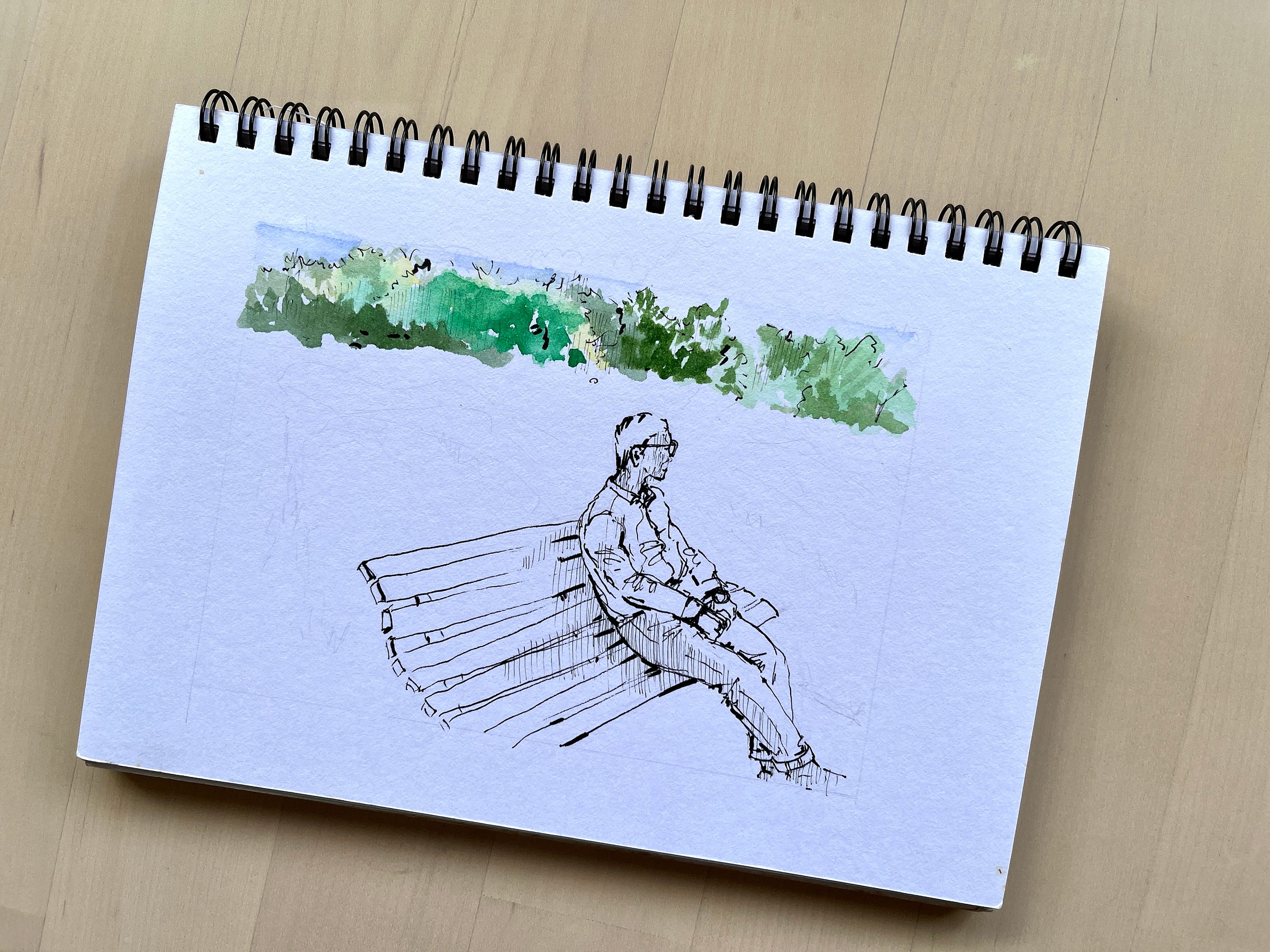 Image: an unfinished drawing/painting of a man sitting on a park bench. The trees in the background are painted with watercolour, and the rest of the drawing with a black fine liner pen.