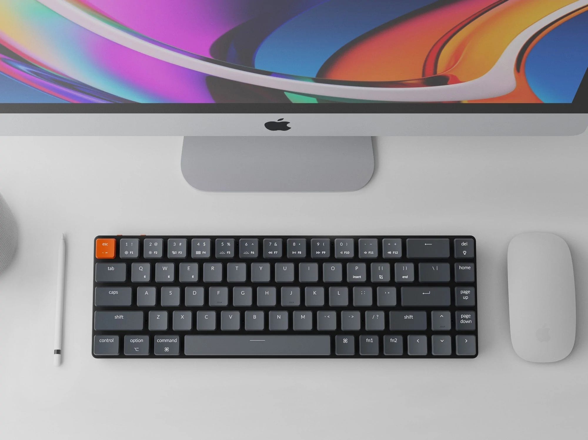 An image of the keyboard Keychron K7 accompanied with a mac magic mouse, an apple pencil and, in the picture, a partial mac desktop screen.