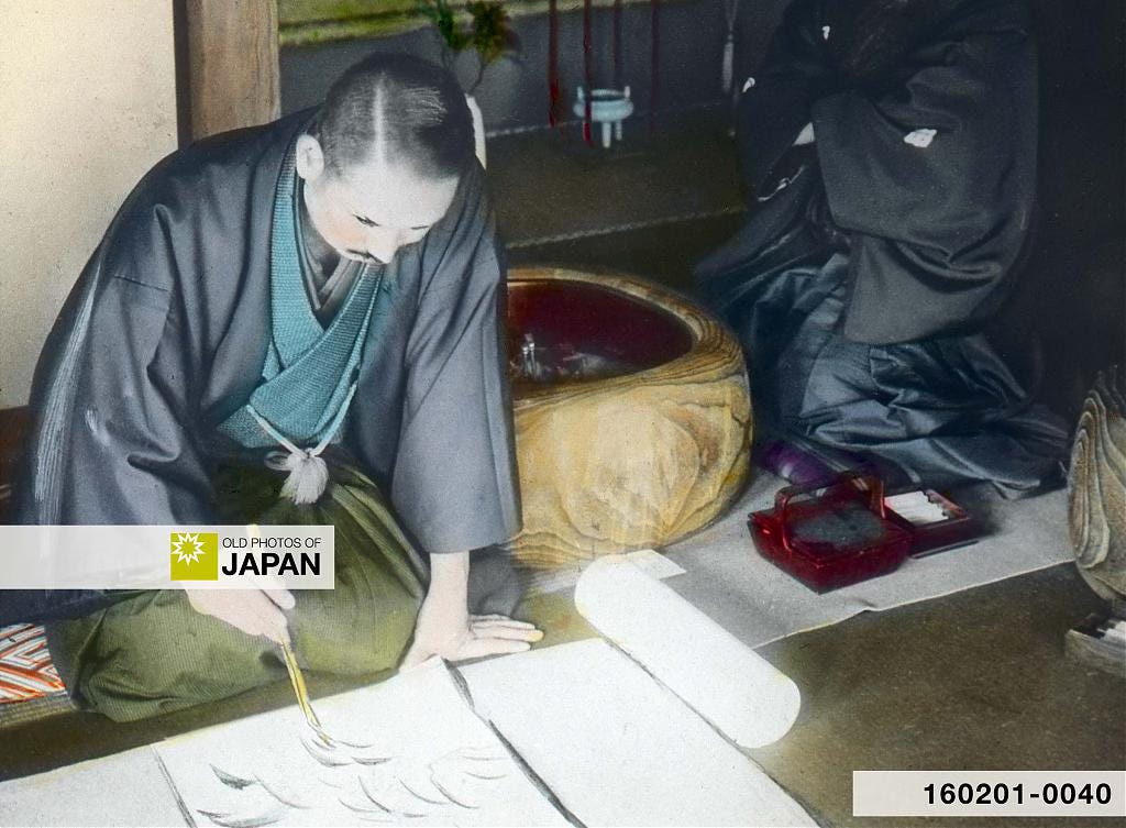 Japanese artist practicing brush strokes while seated next to a kurinuki hibachi, ca. 1920s Japanese artist practicing brush strokes while seated next to a kurinuki hibachi, ca. 1920s