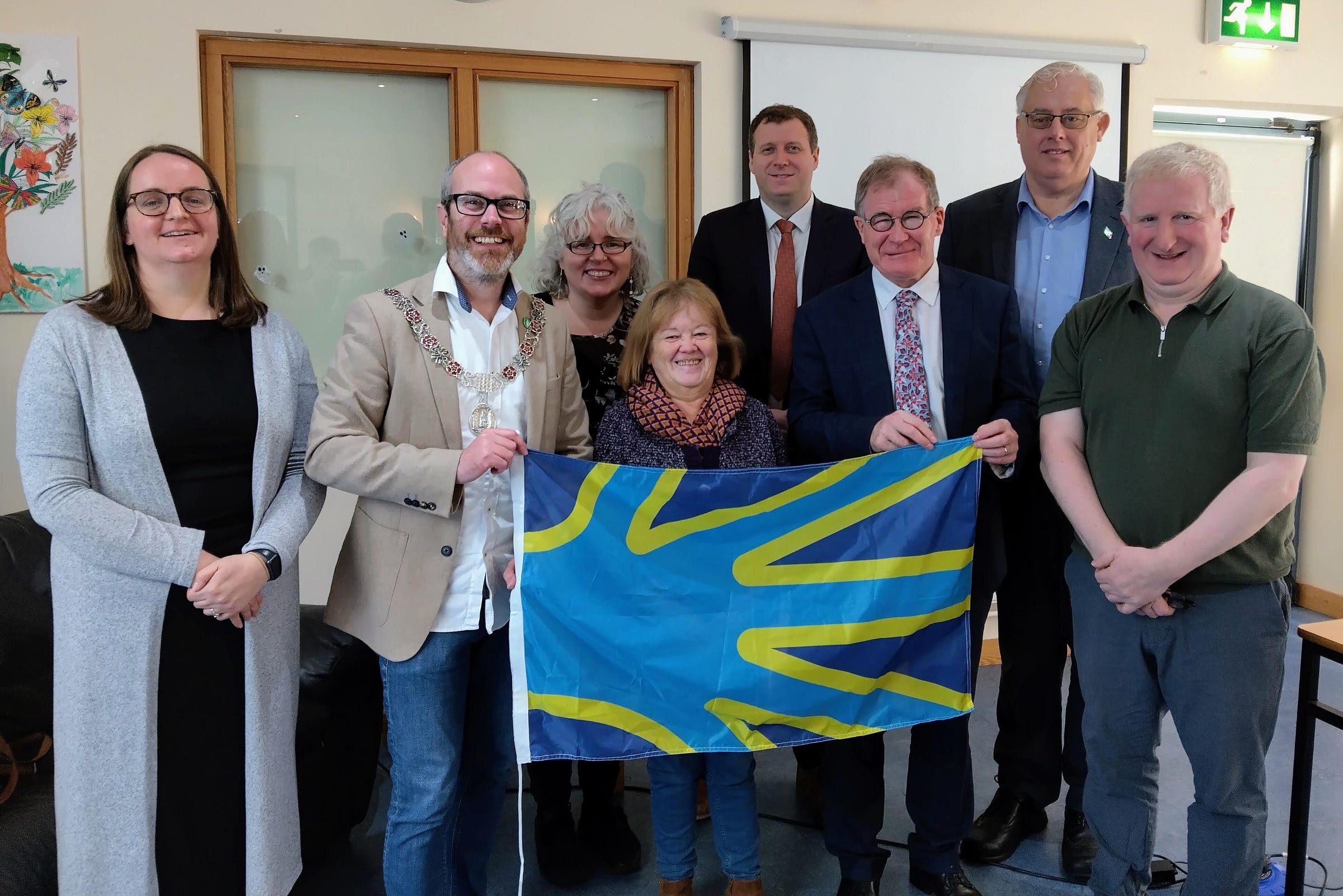 Politicians, HSE staff and members of the Deaf community with the Deaf flag.