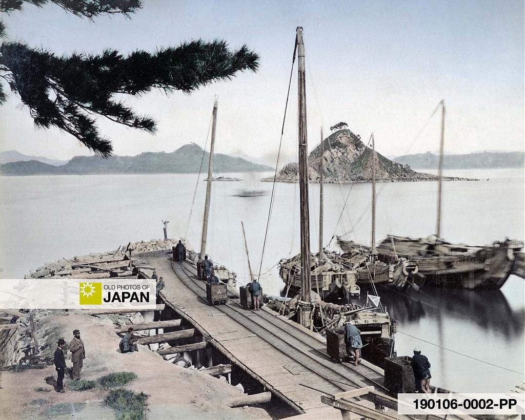Mine workers at Takashima Island push trolleys with coal towards sailing vessels, 1872