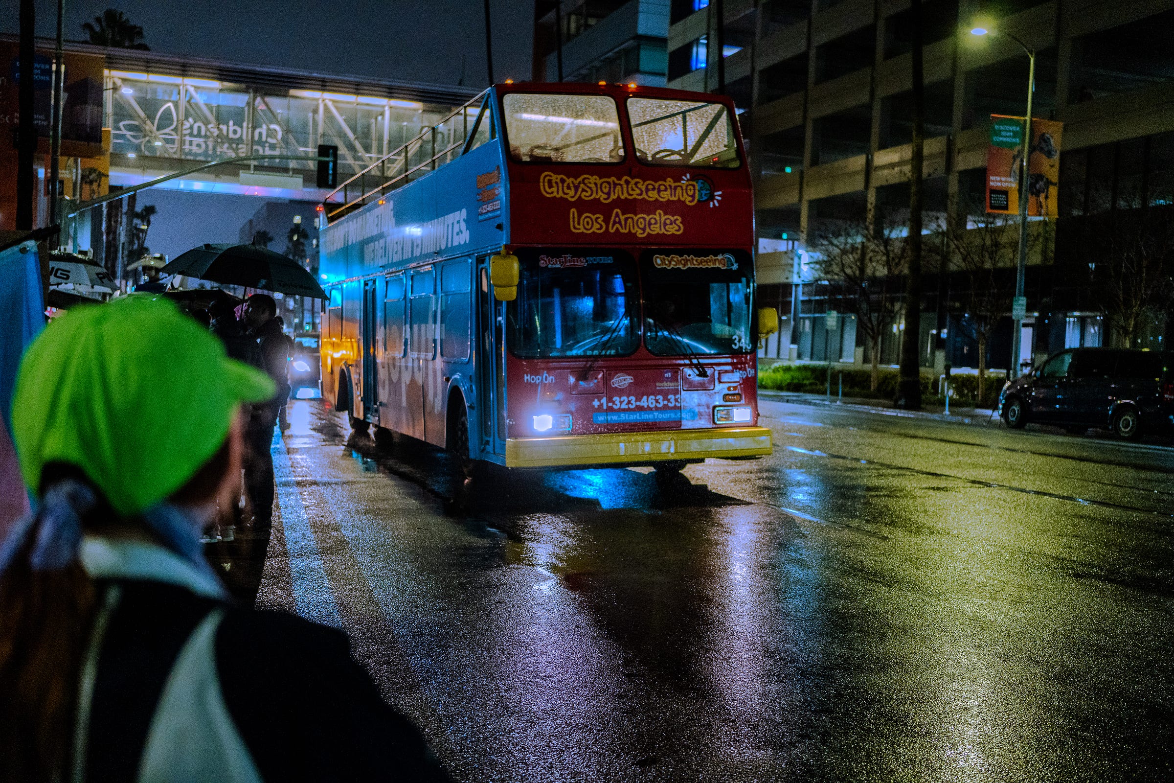 A CitySightseeing Los Angeles bus drives past the protest under the CHLA pedestrian bridge