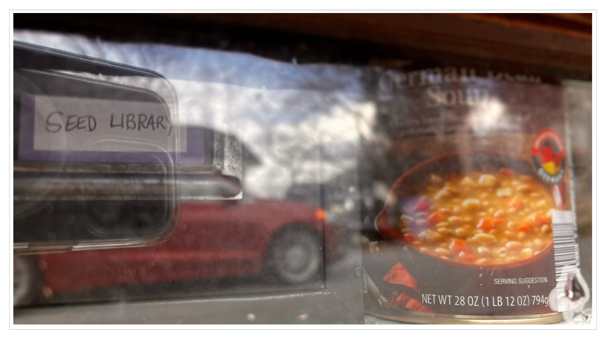 close-up of can of soup behind glass door, cell phon and car reflection