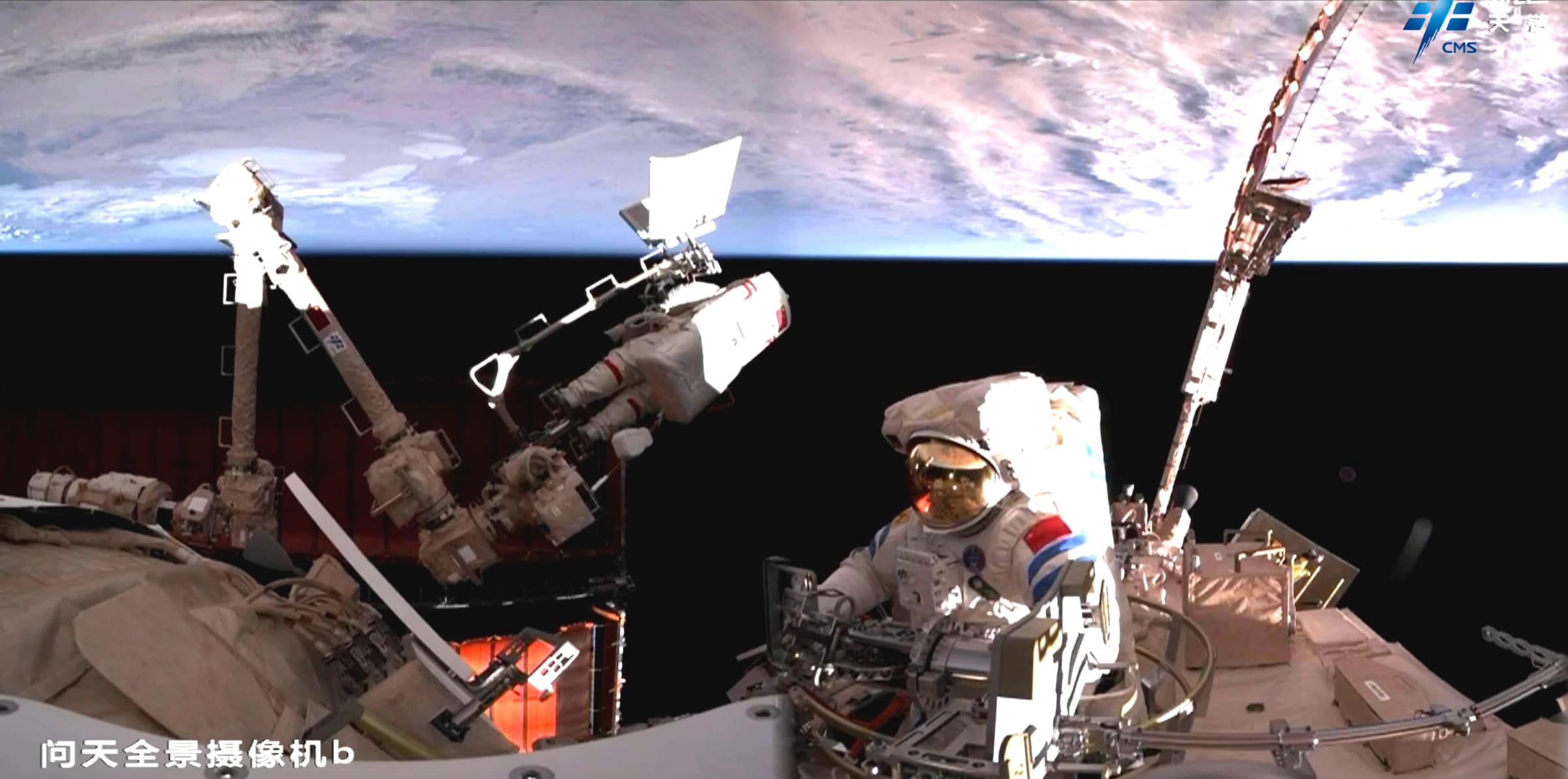 Song Lingdong emerging from the Wentian module while Cai Xuzhe is attached to Tiangong’s robotic arm.