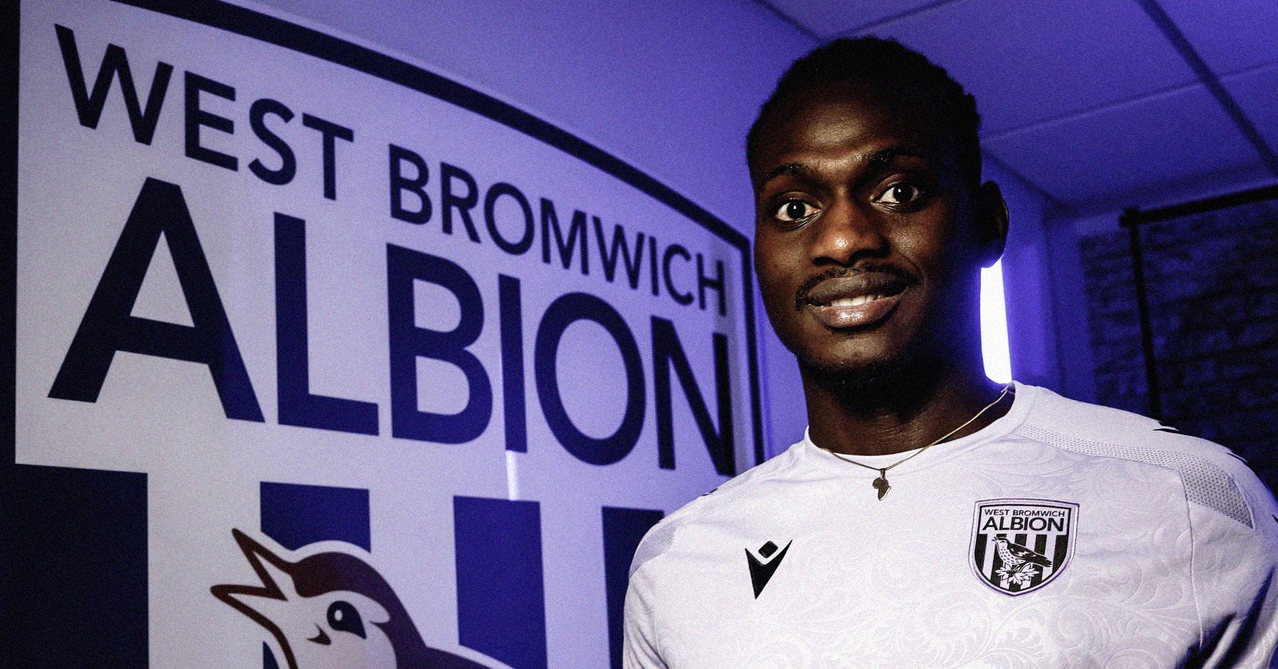 A photo of Ousmane Diakité stood in front of a large West Bromwich Albion emblem