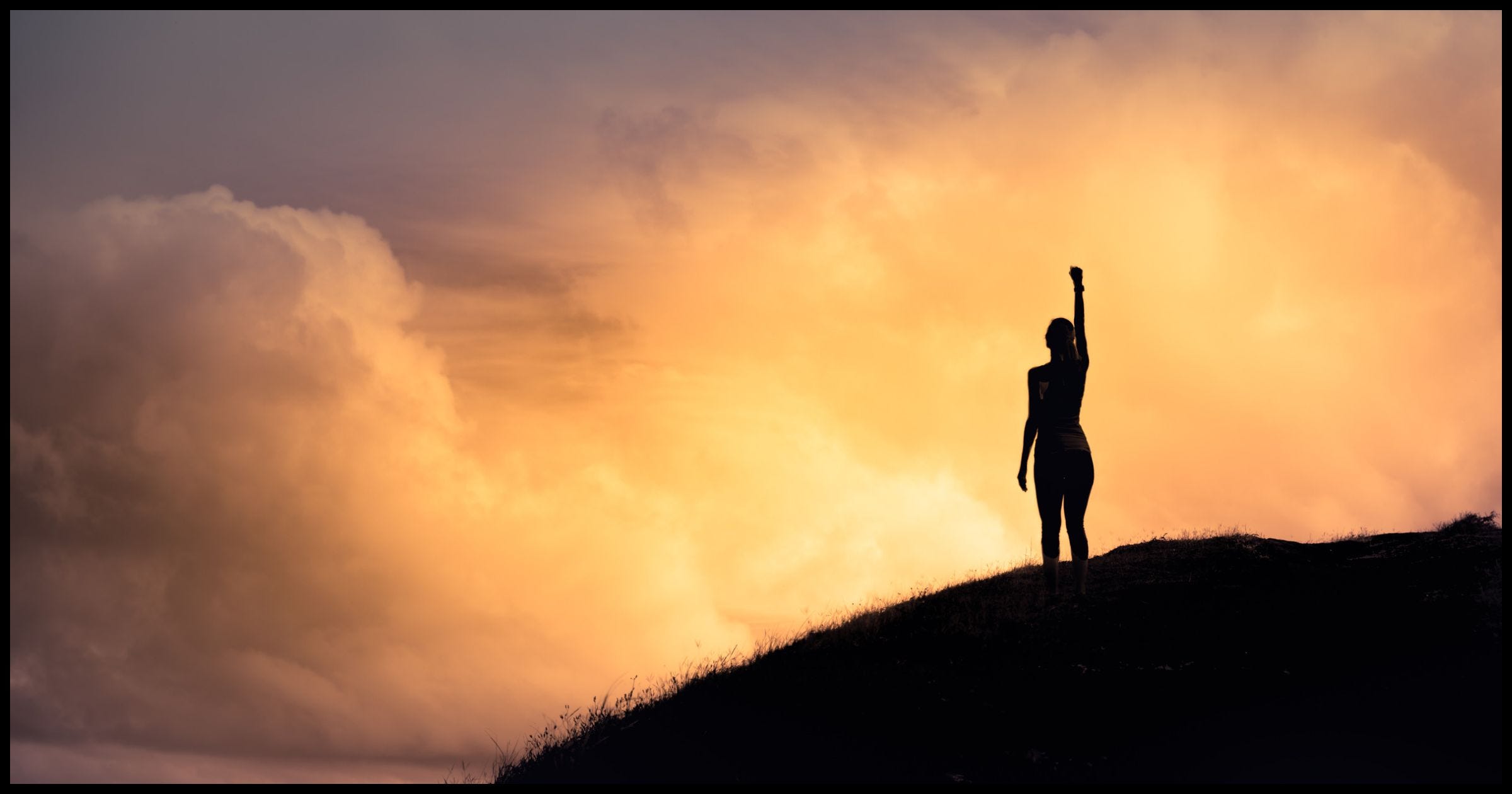 Woman raising her fist at the sunset