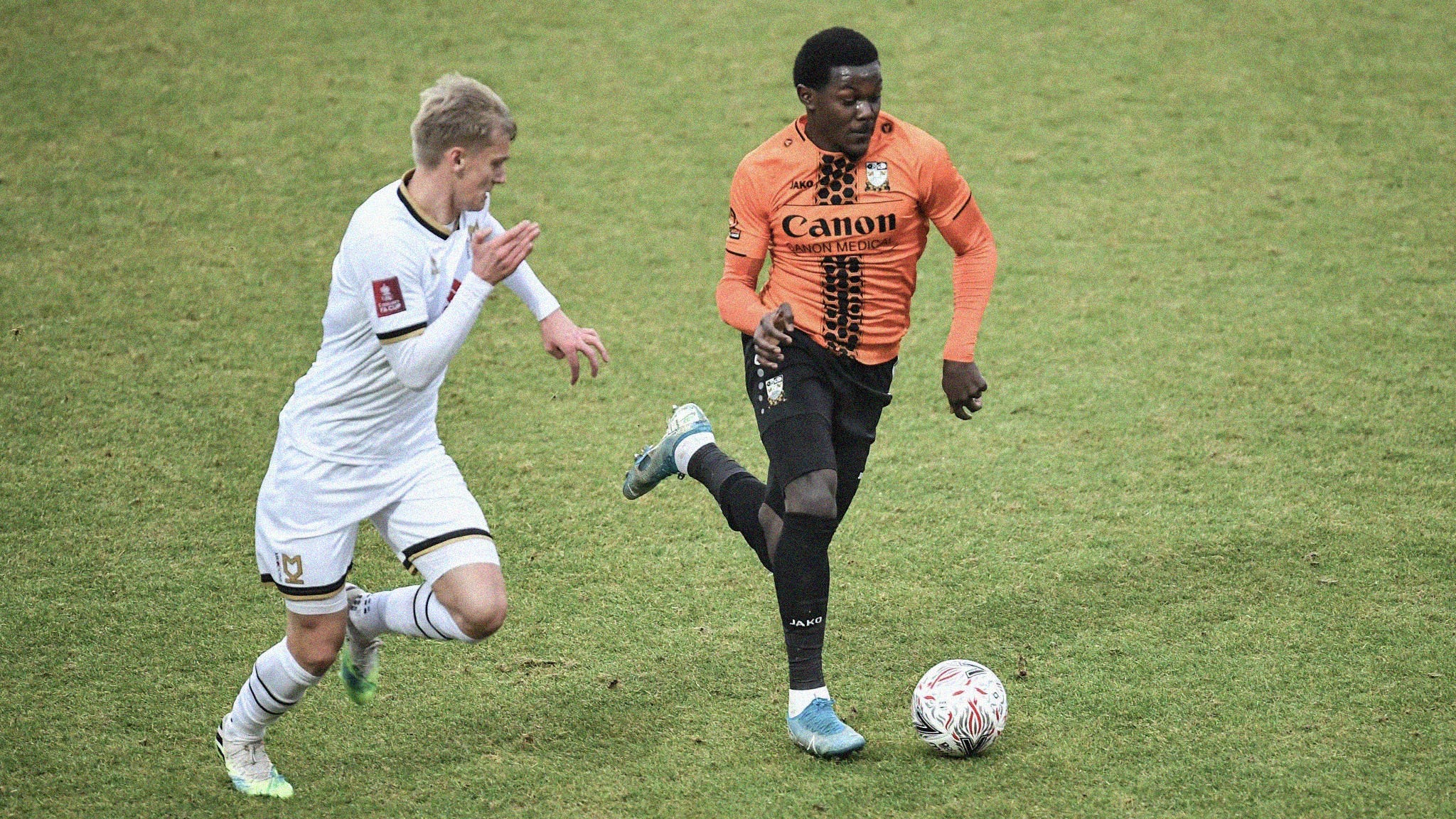 A photo of Ephron Mason-Clark running with the ball for Barnet as an MK Dons player tracks him