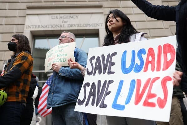 A person holding a sign that reads "Save USAID. Save lives."