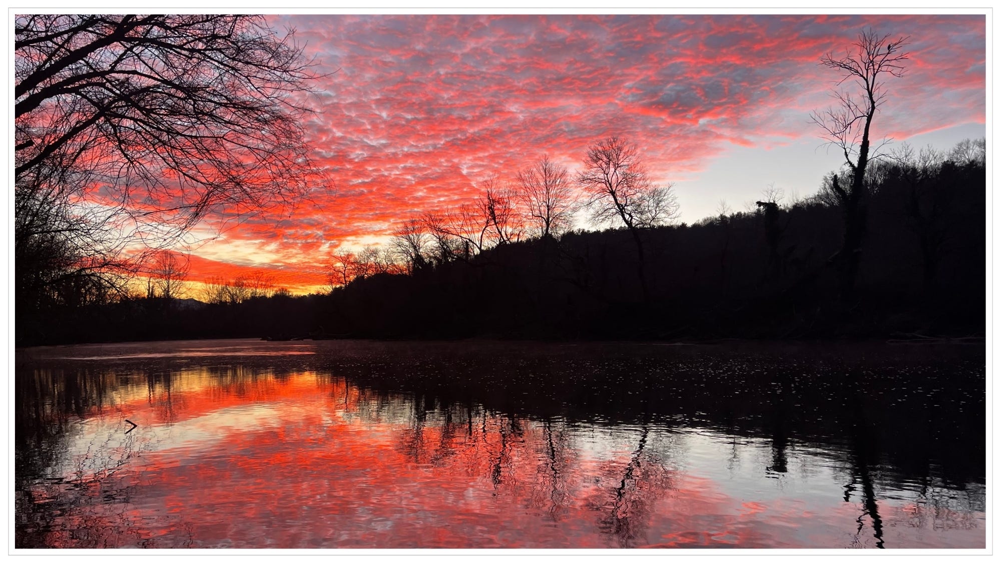 Bright red textured sky at dawn, red reflection in river