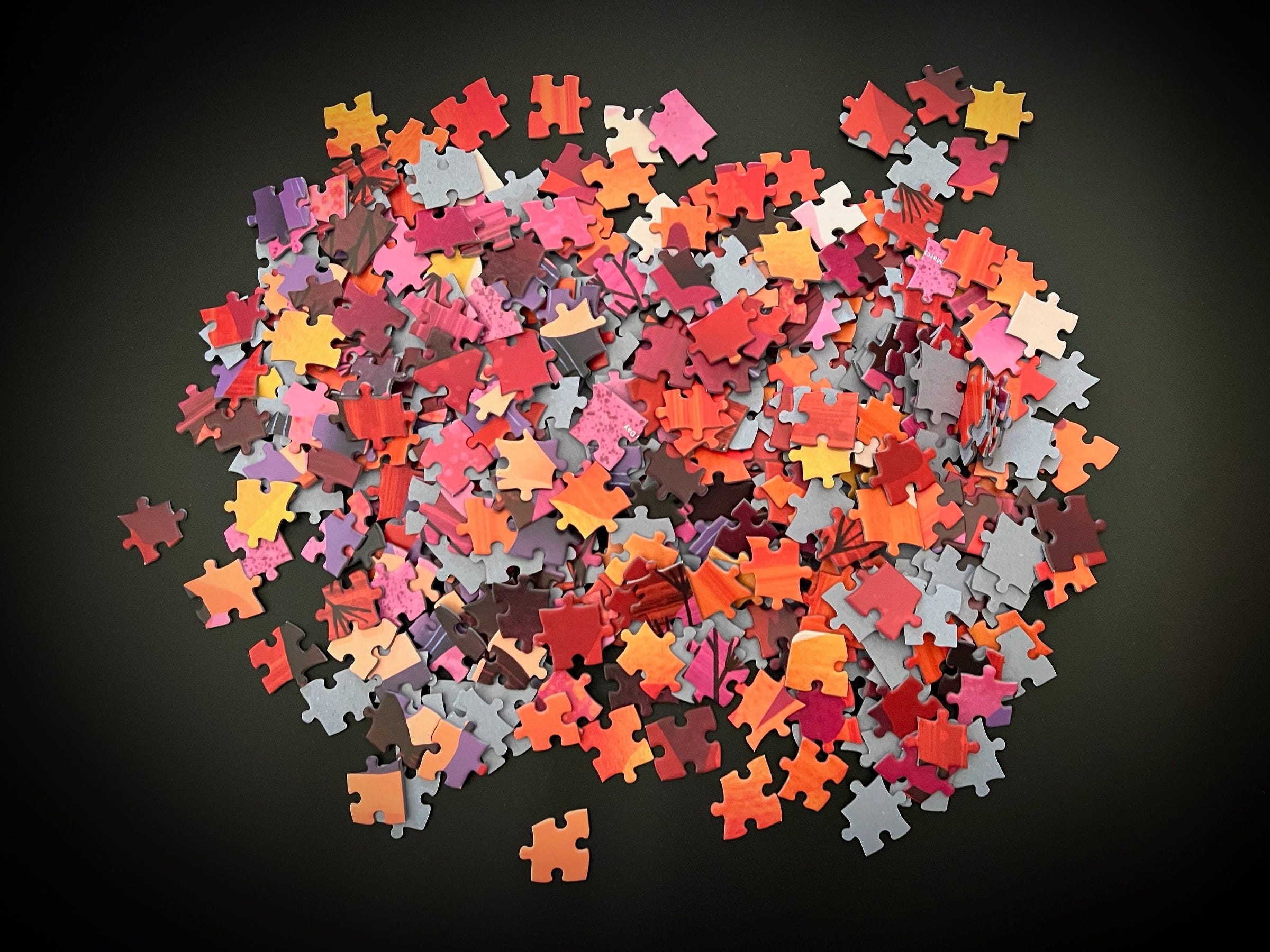 A jumbled pile of jigsaw puzzle pieces against a black background