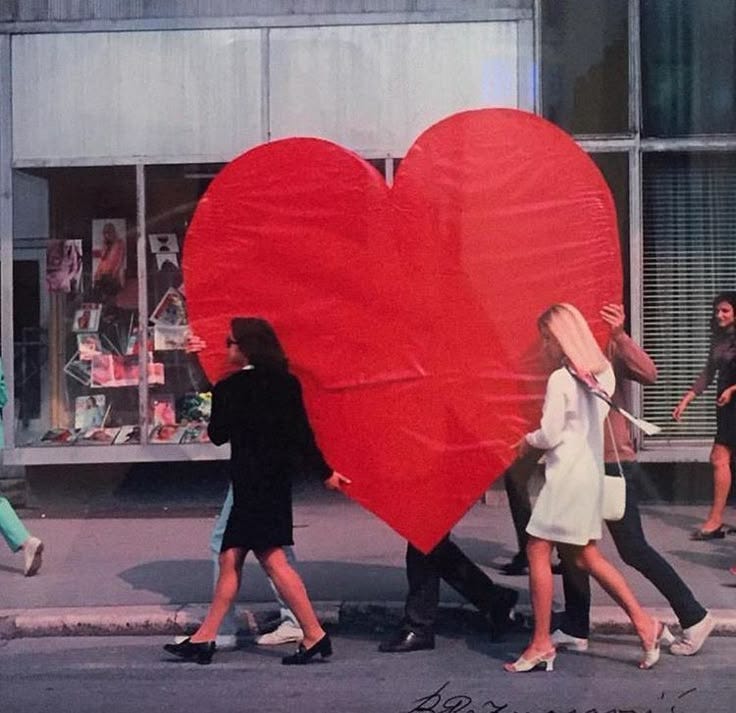This may contain: people walking down the street with a giant heart