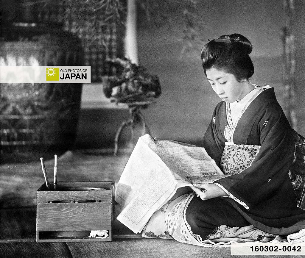 A Japanese woman reads a newspaper next to a simple square wooden hibachi A Japanese woman reads a newspaper next to a simple square wooden hibachi