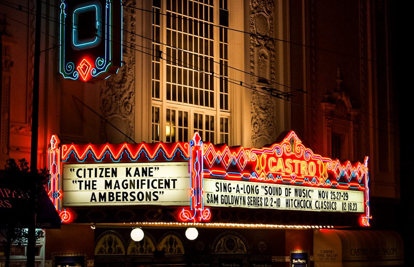 A night view of the Castro Theatre's neon marquee in San Francisco, lit up in red, blue, and yellow. The marquee displays the titles "Citizen Kane" and "The Magnificent Ambersons," with additional listings for sing-alongs and Hitchcock classics. A night view of the Castro Theatre's neon marquee in San Francisco, lit up in red, blue, and yellow. The marquee displays the titles "Citizen Kane" and "The Magnificent Ambersons," with additional listings for sing-alongs and Hitchcock classics.