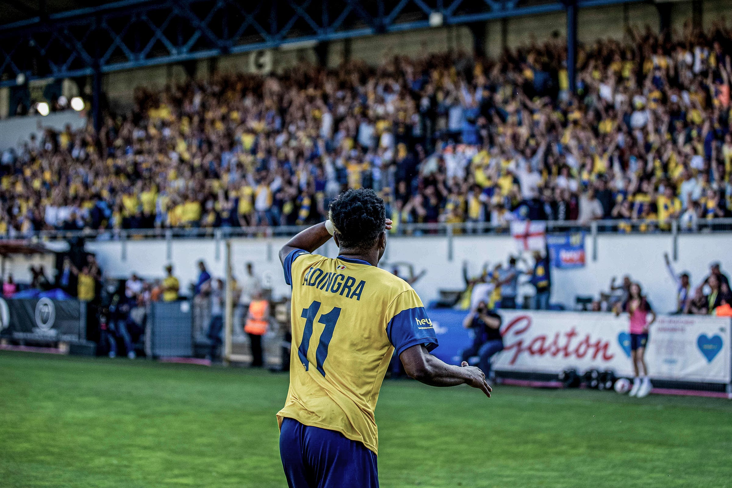 A photo of Simon Adingra from behind with fans celebrating in the background