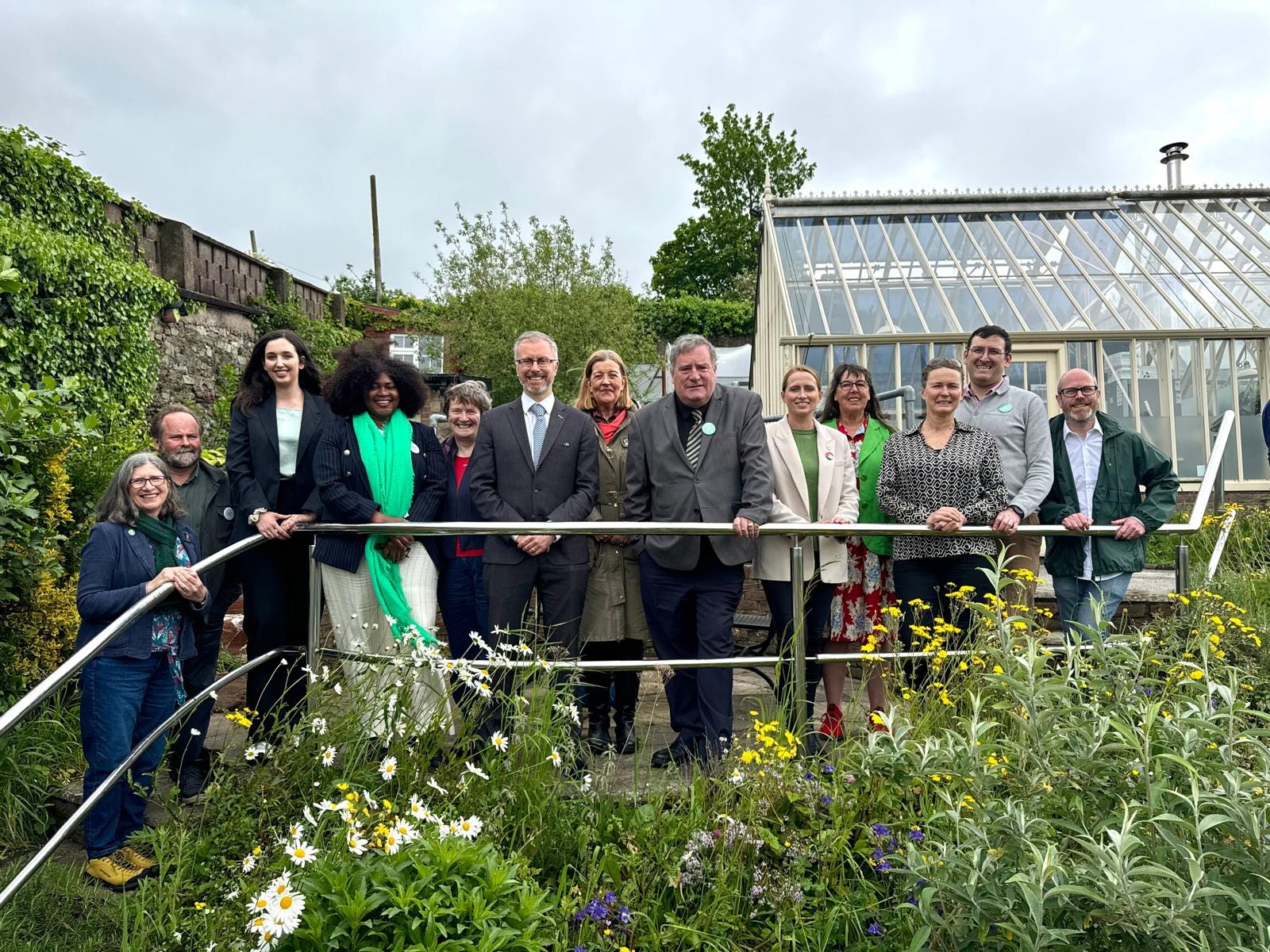 Green Party candidates with Roderic O'Gorman near a garden glasshouse.