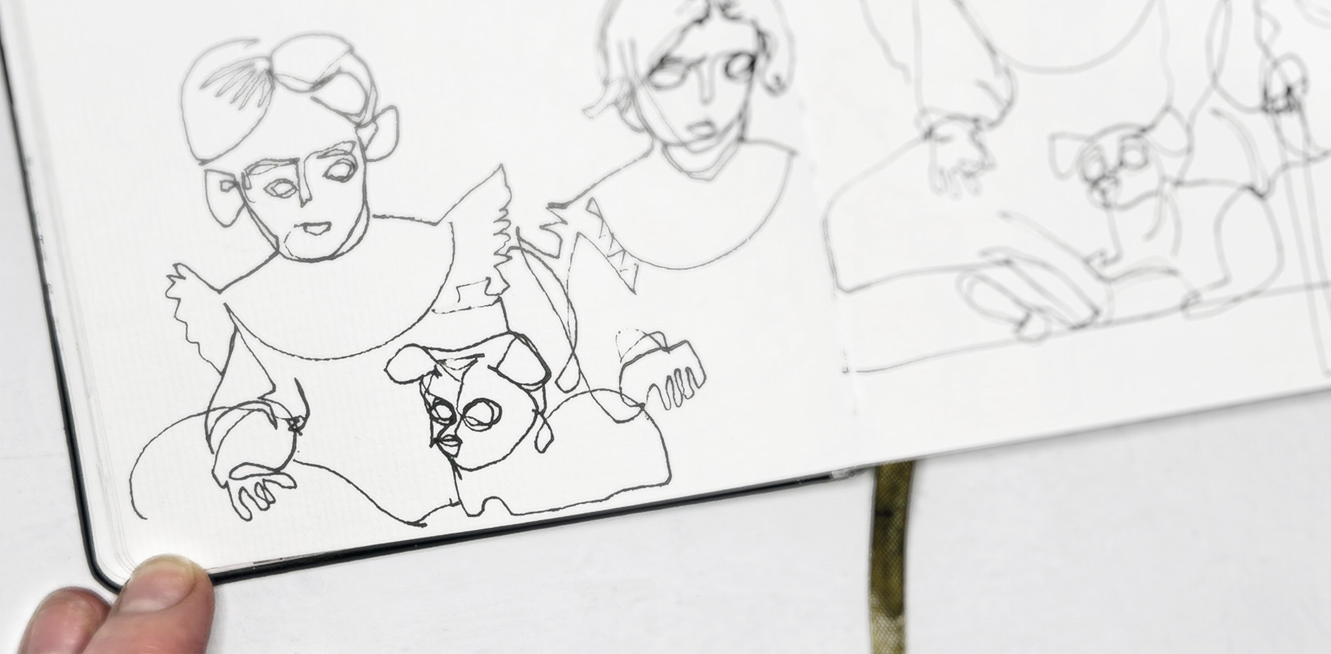 Photograph showing a blurry close-up of blind contour drawings in ink, drawn in a small sketchbook