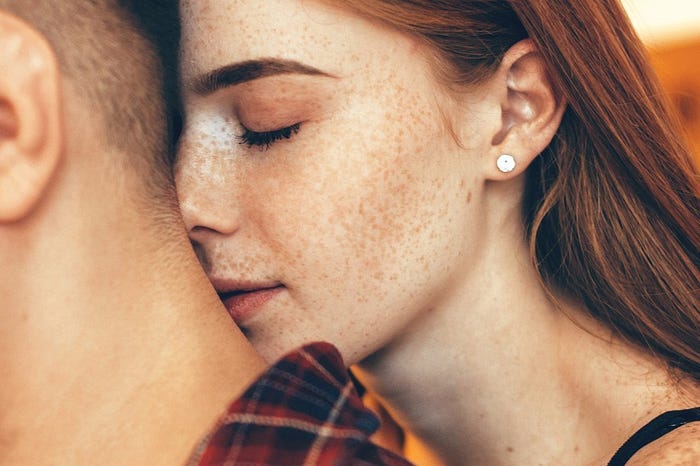 A beautiful girl with freckles with her face up against a guy's neck A beautiful girl with freckles with her face up against a guy's neck