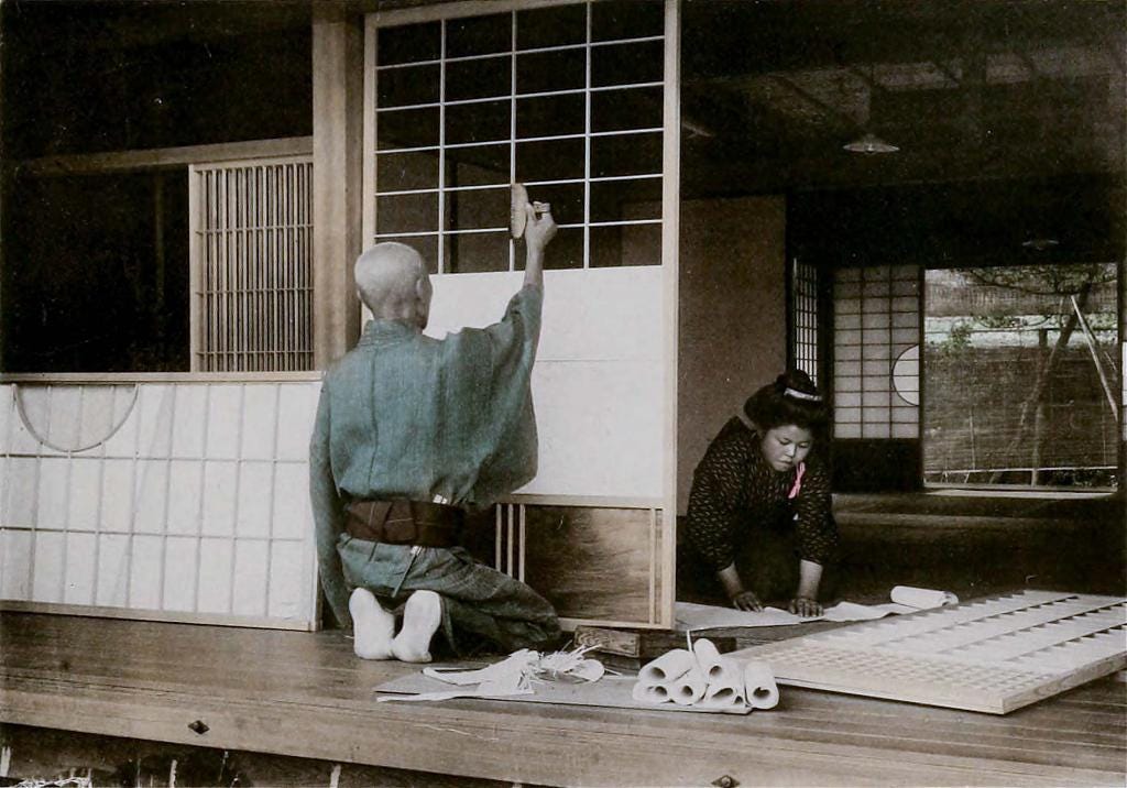 Placing translucent paper on a latticed frame of a shōji at a middle class home in Kobe, ca. 1900