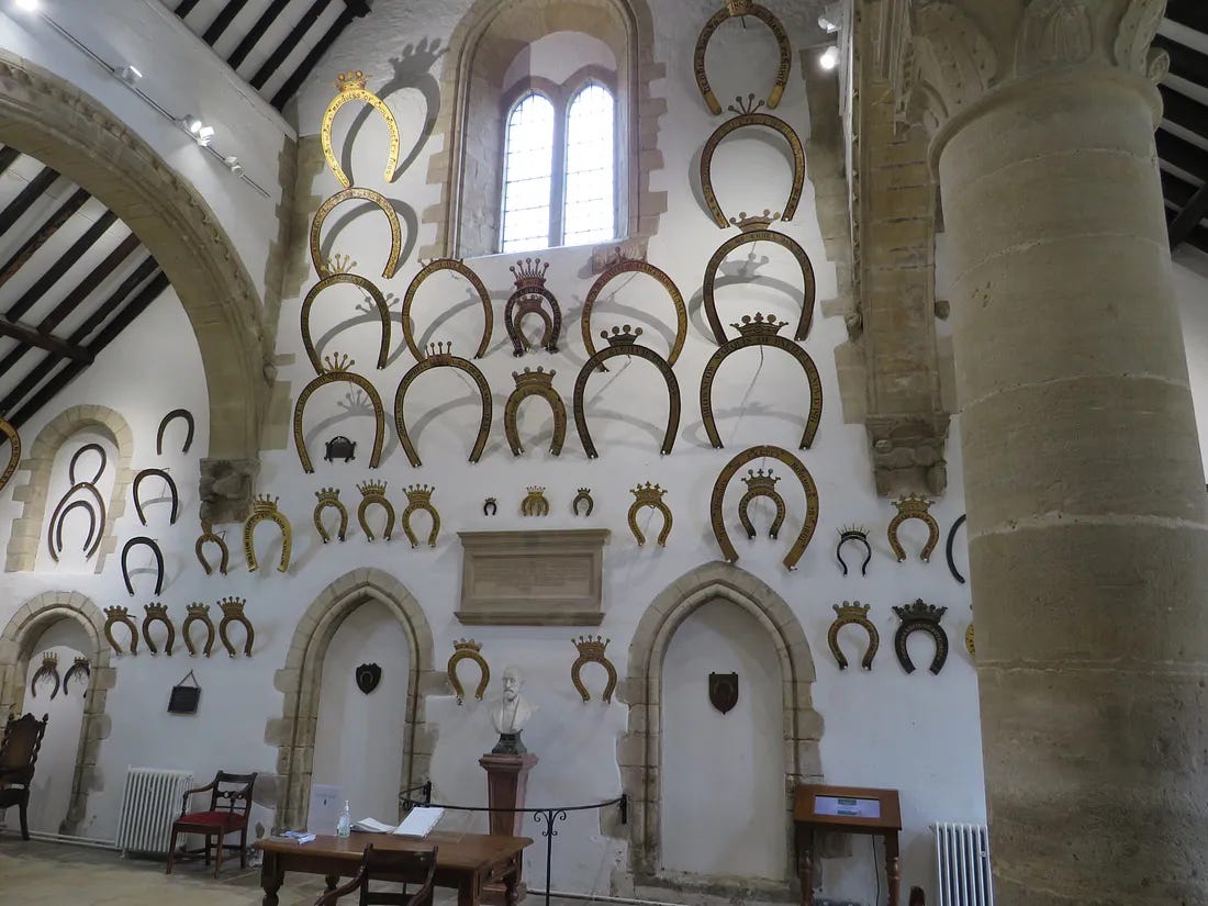 Oakham Castle: interior east wall of horseshoe tributes. Door spaces originally led to kitchens and buttery. 