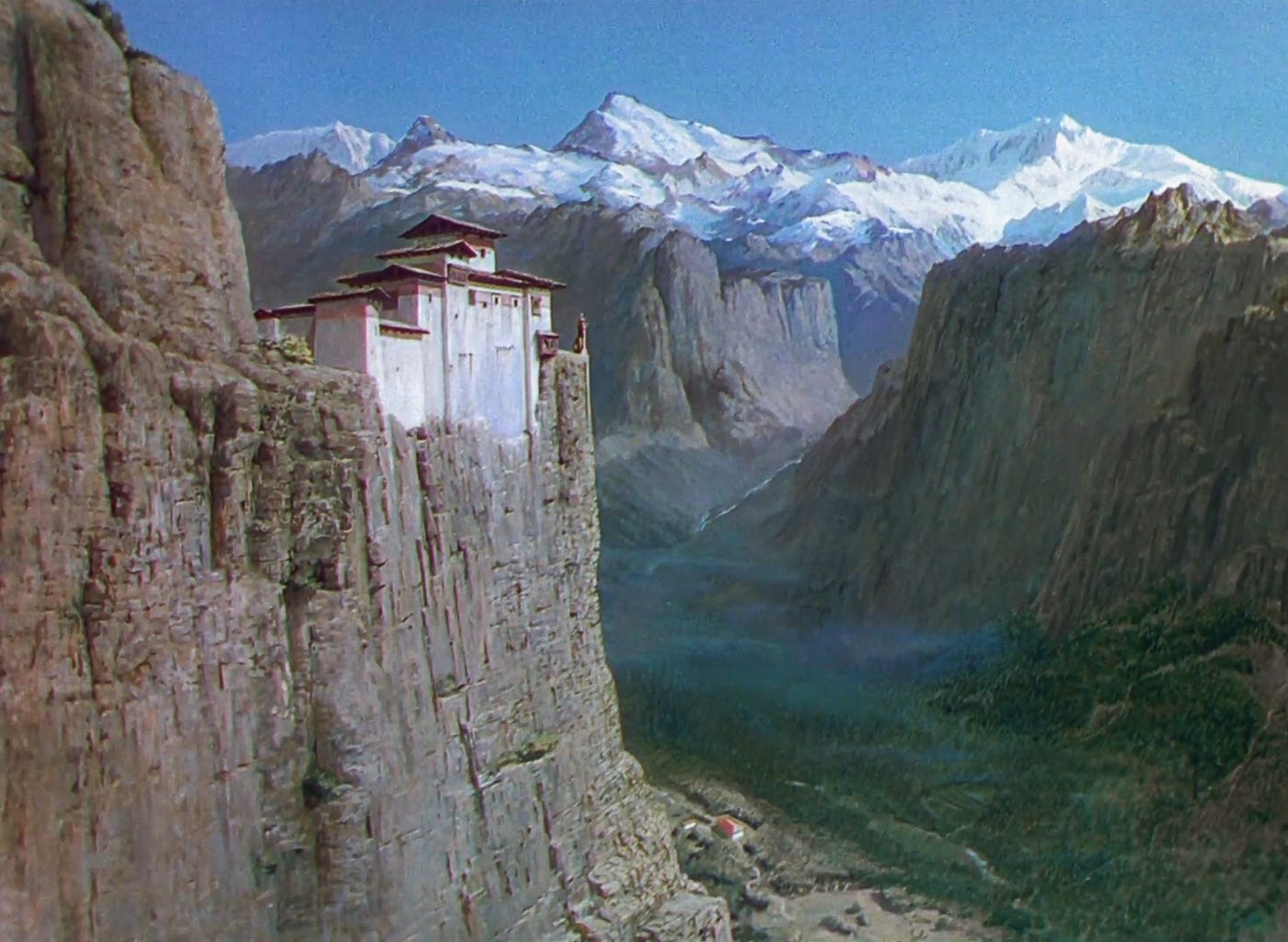 The palace of Mopu sits on the edge of a preciptous cliff with the snow-capped Himalayas in the background above a verdant green valley below. The palace of Mopu sits on the edge of a preciptous cliff with the snow-capped Himalayas in the background above a verdant green valley below.