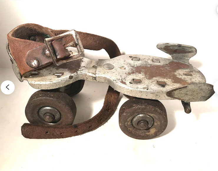 Photo of a vintage metal roller skate with a brown leather strap.