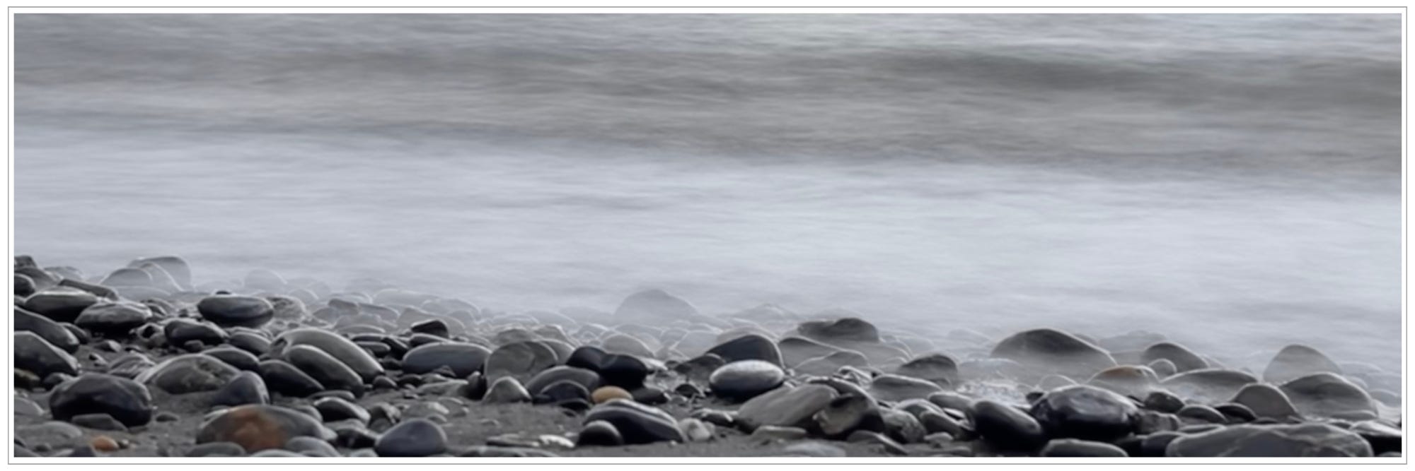 mist on waves gently rolling over stony shore