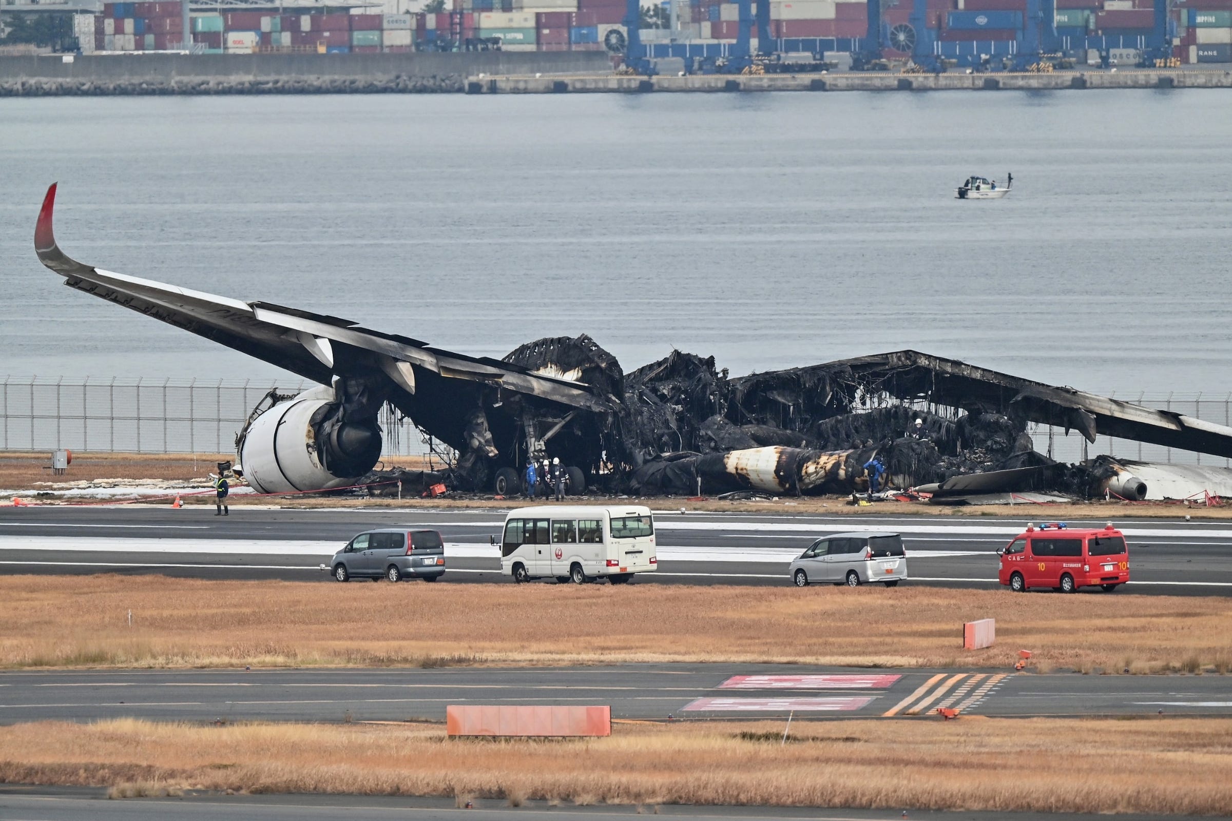 PHOTO: Officials look at the burnt wreckage of a Japan Airlines passenger plane on the tarmac at Tokyo International Airport at Haneda in Tokyo on January 3, 2024.