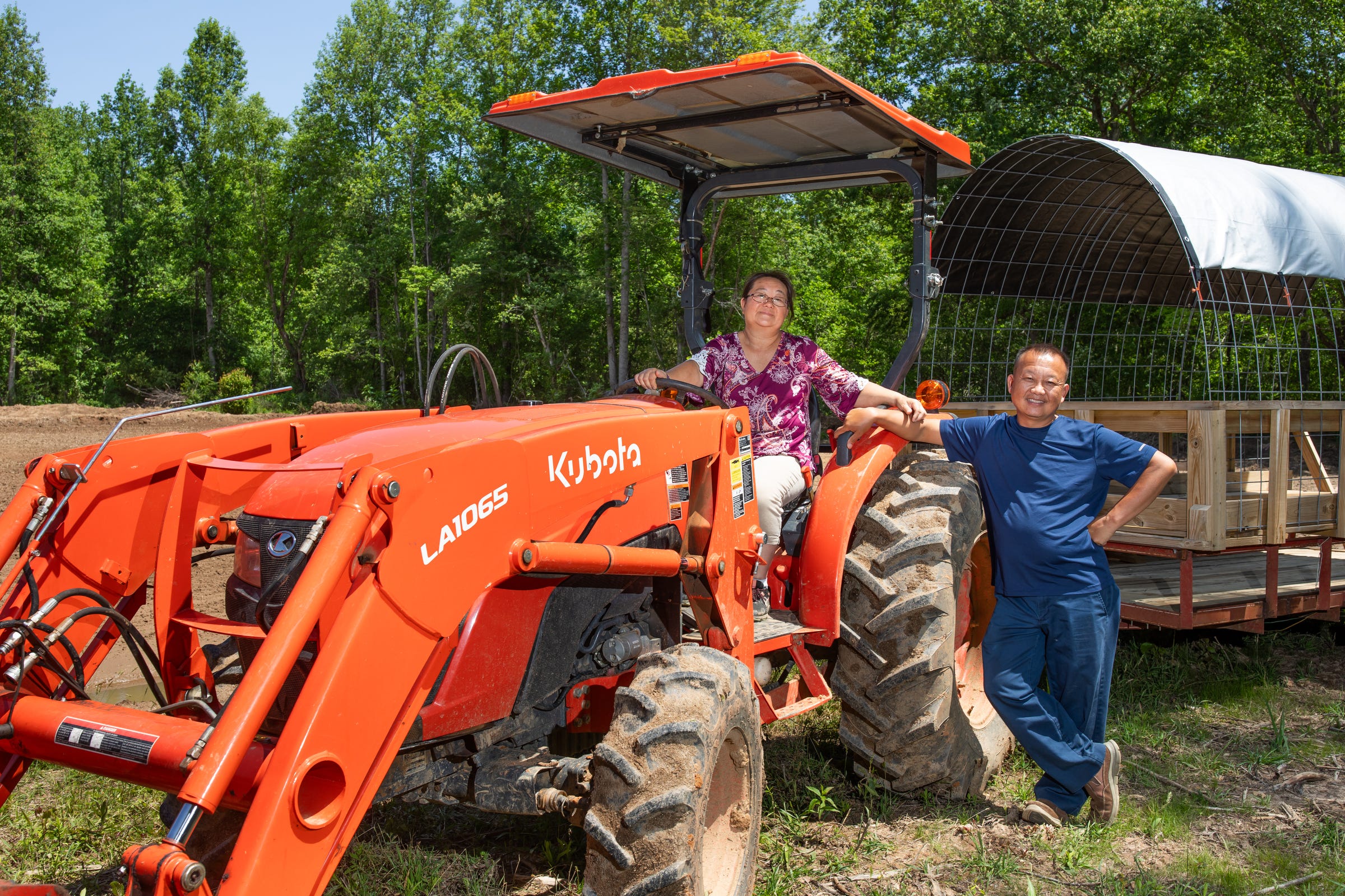 Tou and Chue Lee posing with a tractor on their farm.