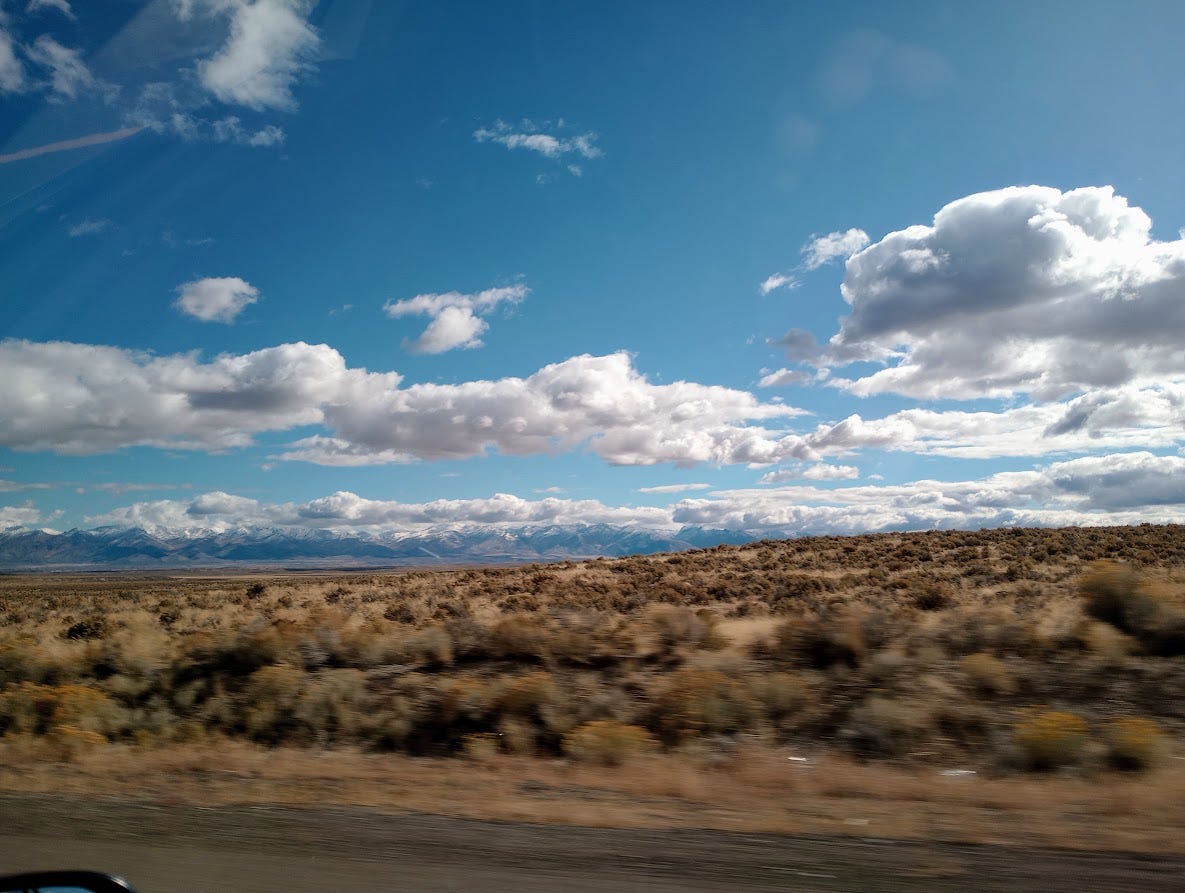 Desert with scrub,  sunny skies, clouds, mountains