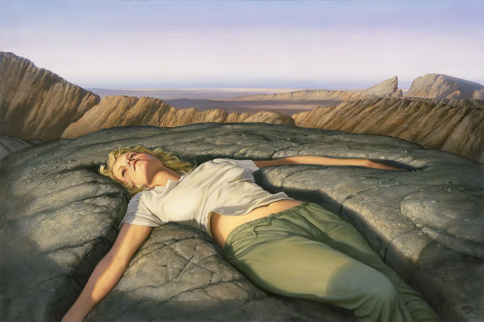 Sunken into solid rock, a woman with wavy golden blonde hair lies with her arms spread and stares up at the sky. Her plain white t-shirt rides up to expose a hint of midriff. One knee is slightly raised, and a shadow falls across her thin, drab green sweatpants. The rock enveloping her shows some cracking and pebbling but is mostly worn smooth. A ridge of mountains runs just beyond forming a rim, tan against the gray rock in which she is situated. Past that more barren land leads to a stretch of mountain that climbs left to right with the visible break of a valley cut through before resuming in a long half dome. The panoramic view eventually gives way to soft blue skies.