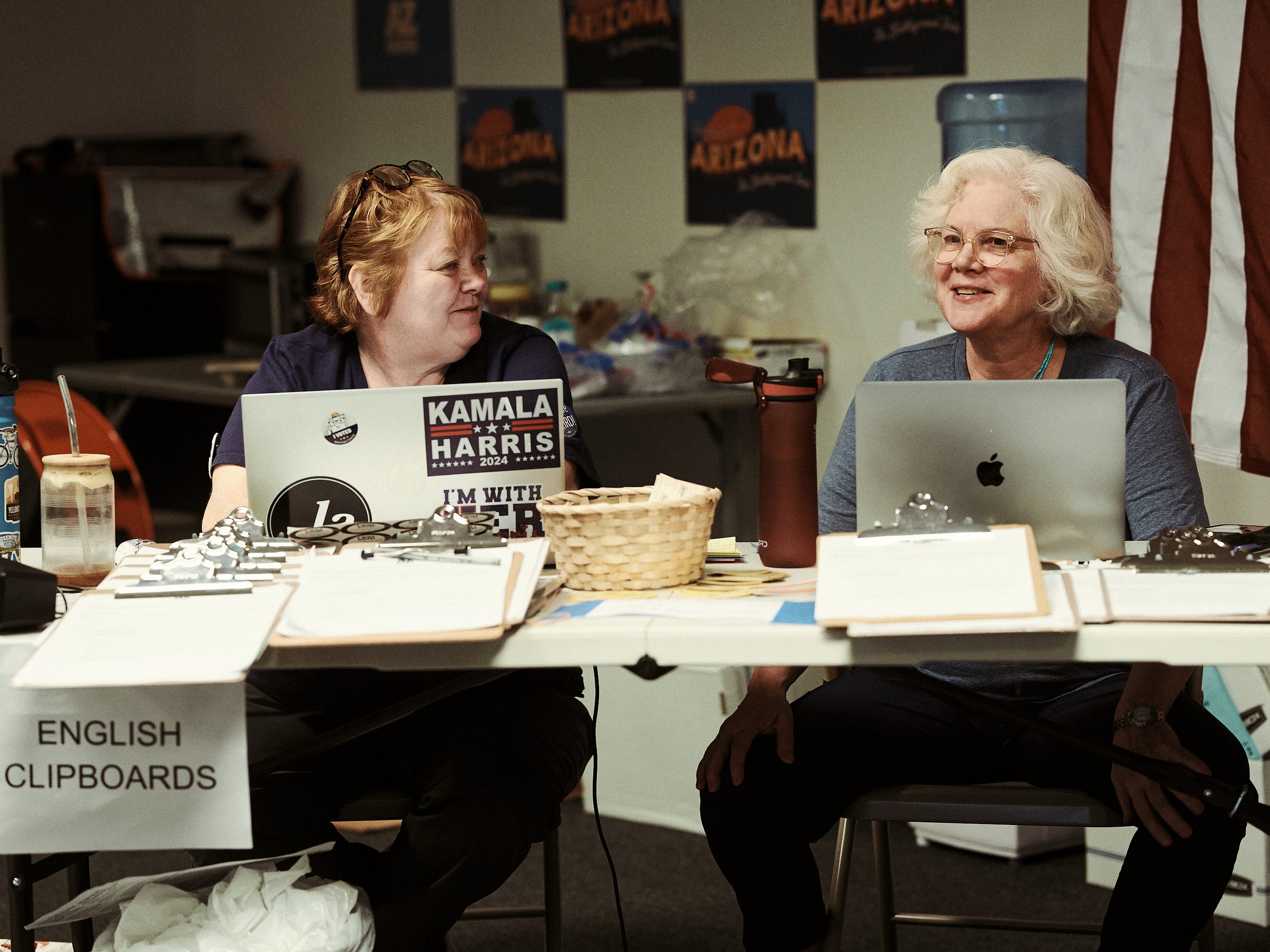 Two campaign workers smile behind a desk while they hand out english packet lists to canvassers photographed by LA photographer Afonso Salcedo