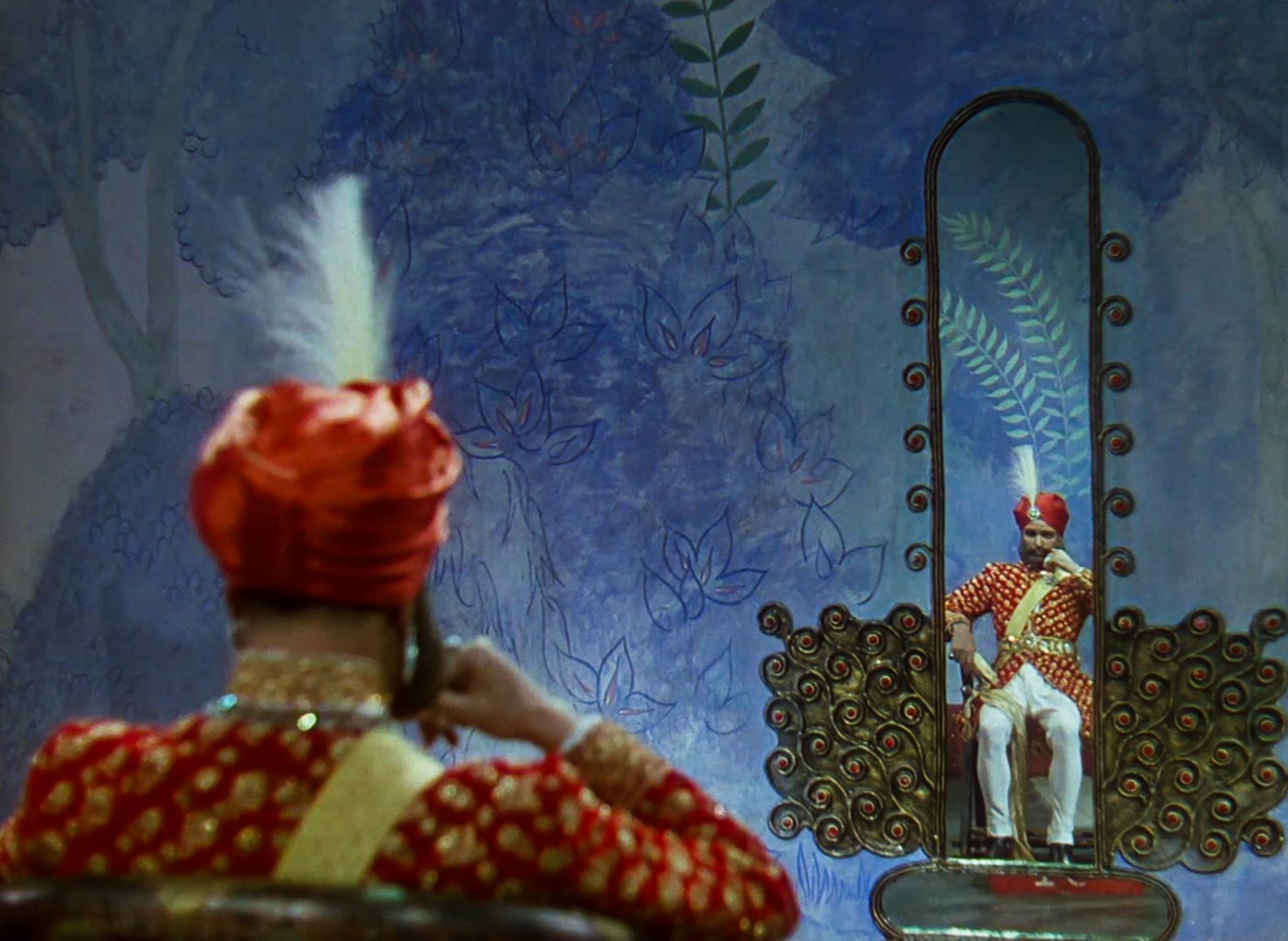 The costumed Old General is seated in the violet reception room at the palace of Mopu staring at his reflection in an unsmistakably phallic ornate wall mirror. The costumed Old General is seated in the violet reception room at the palace of Mopu staring at his reflection in an unsmistakably phallic ornate wall mirror.