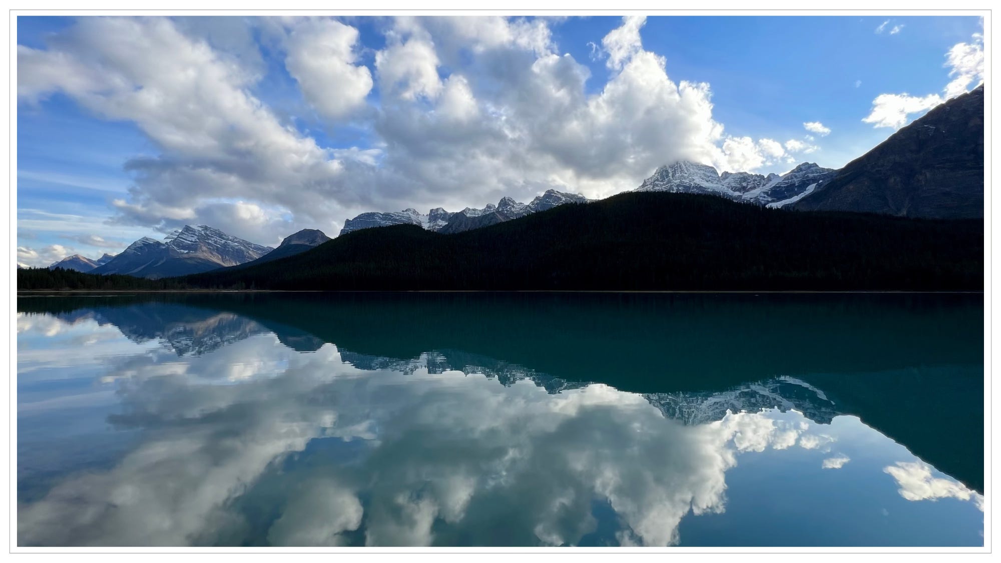 still water, reflecting clouds and mountains