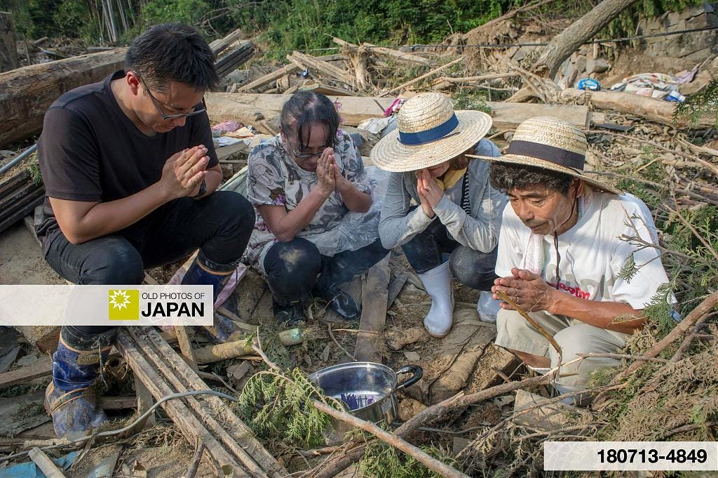 A family prays for a family member killed by mudslides in Nakahata Ichibara in July 2018