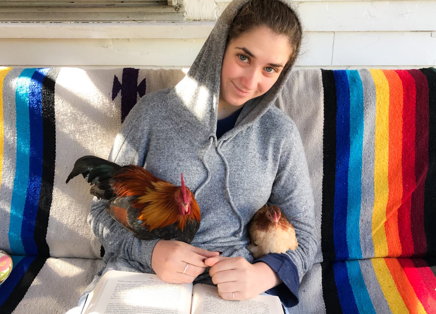 young woman on couch holding two small chickens