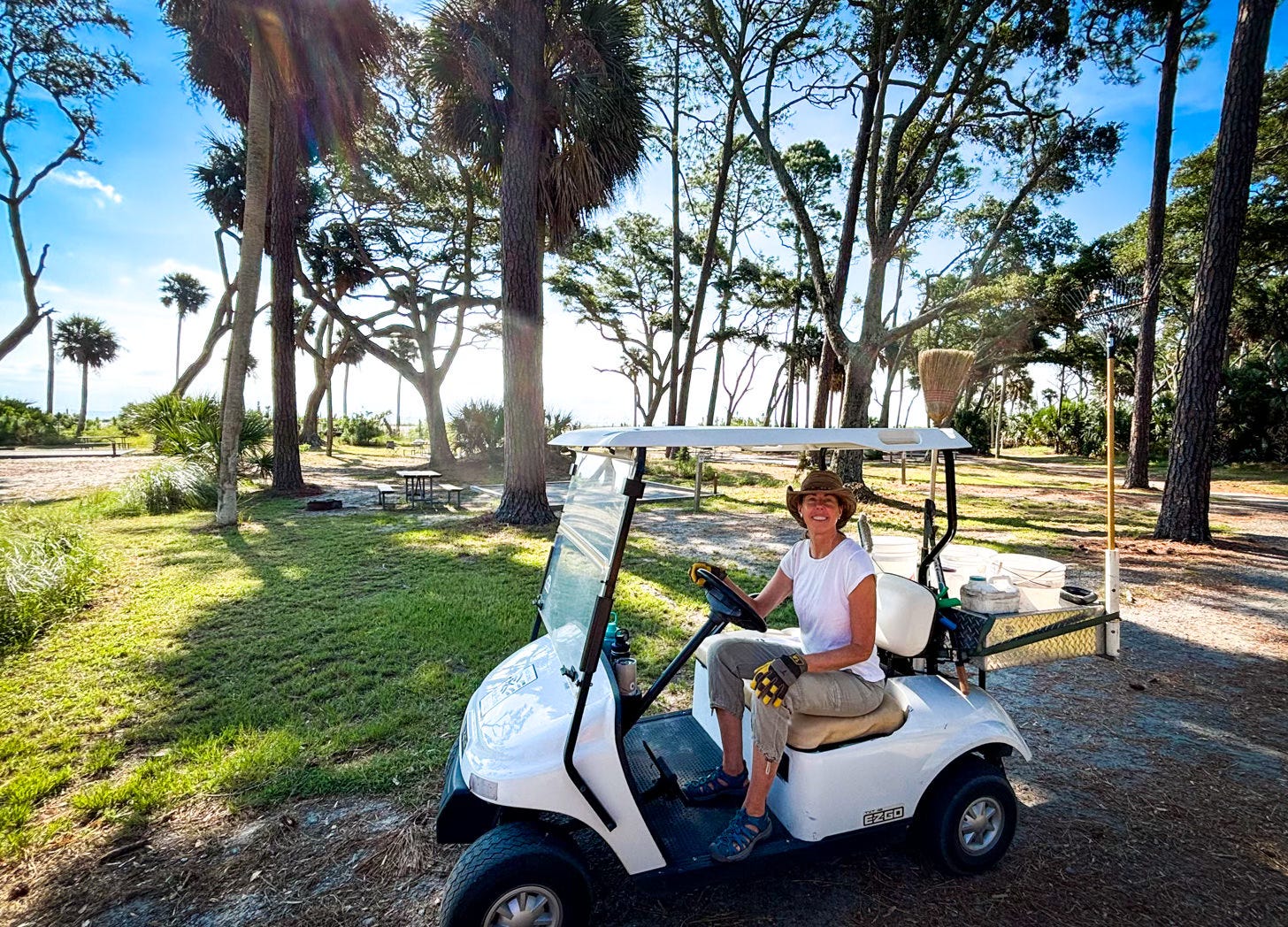 A woman sitting in golf cart in a campground with palm trees