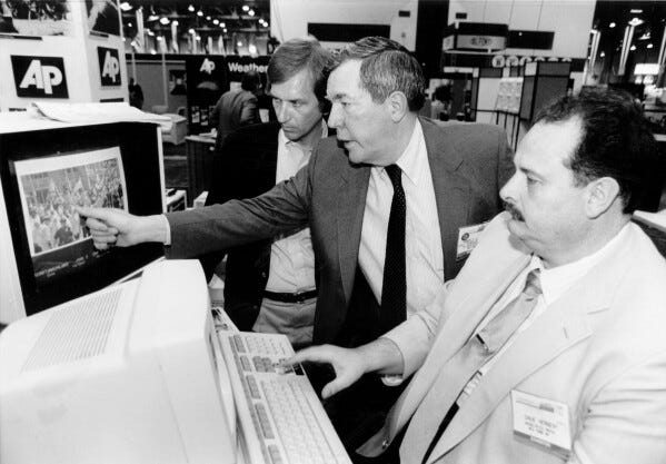 FILE - The Associated Press' assistant general manager for news photos Hal Buell, center, and Dave Herbert, right, the consultant who wrote the electronic darkroom software, explain PhotoStream at the American Newspaper Publishers Association technical convention in Las Vegas in June 1987. Buell, who led The Associated Press' photo operations from the darkroom era into the age of digital photography over a four-decade career with the news organization that included 12 Pulitzer Prizes and running some of the defining images of the Vietnam War, has died. Buell died Monday, Jan. 29, 2024, in Sunnyvale, Calif., where his daughter lived, after battling pneumonia. He was 92. (AP Photo)