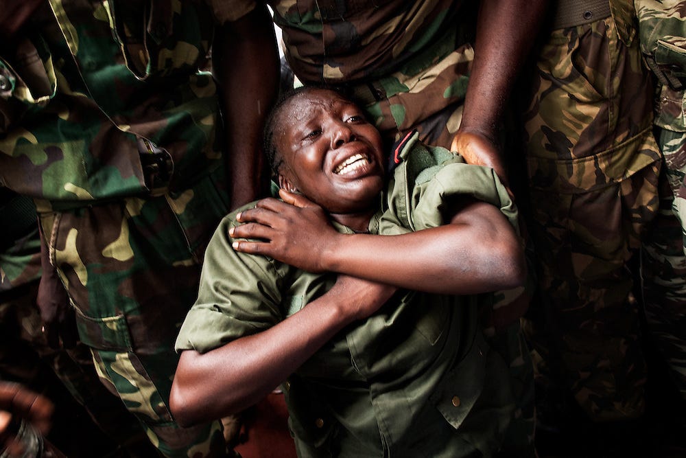 “November 15th 2013, in Bangui at the funerals of Tanguy Residou, a former FACA soldier killed by the Seleka the week before, a female soldier falls out of emotions on the ground, while her brothers in arms try to catch her.” From ‘On est ensemble’. © Camille Lepage