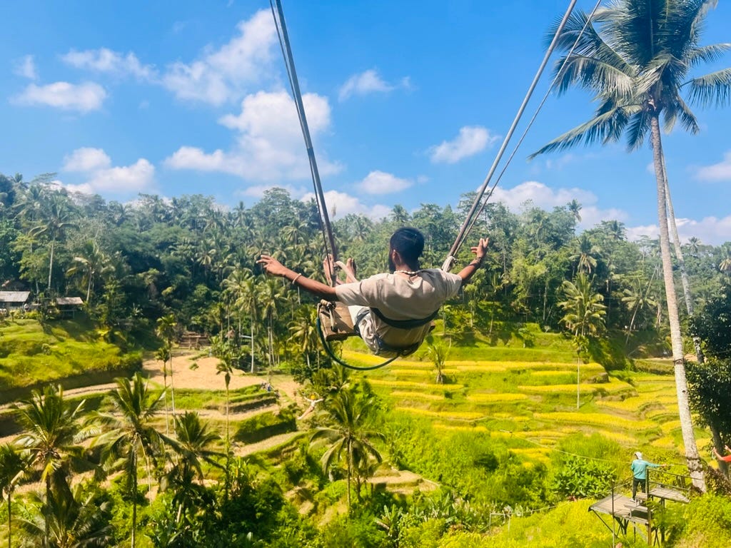 A picture of me on a high swing above the vivid background of an expansive green rice terrace