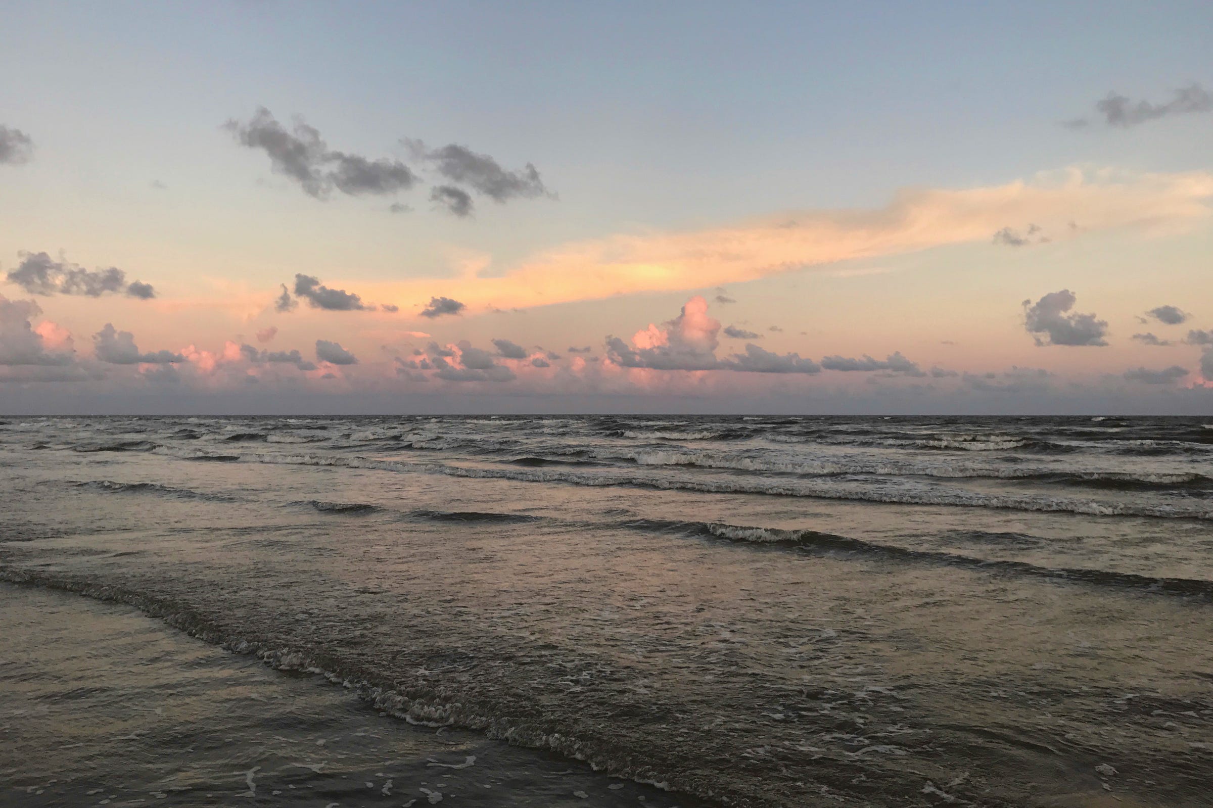 Sunset  on an ocean beach with blue sky and the reflection of the sun in the coral and pink clouds