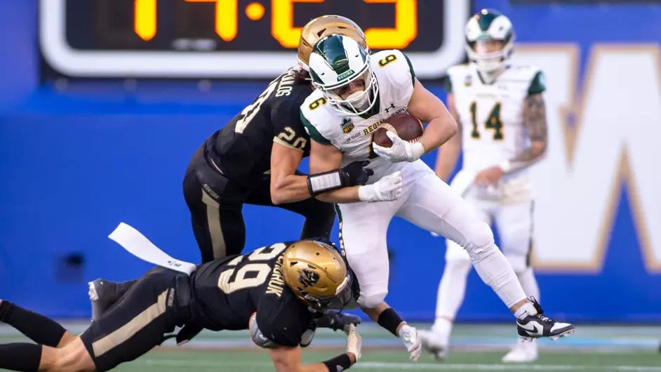 Football player running with the ball makes contact with two defensive players.