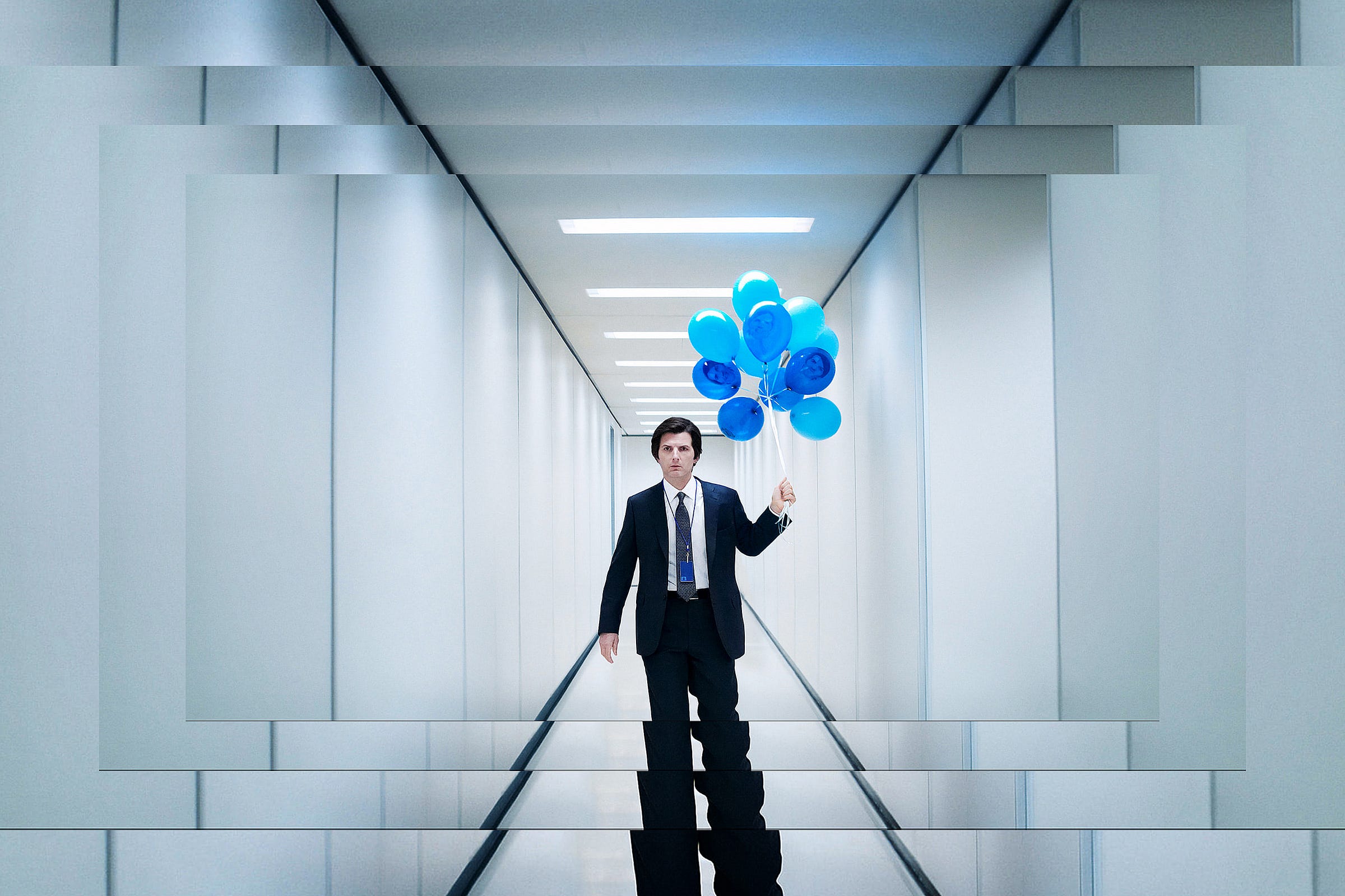 A staggered photograph of a man wearing a suit and tie as he walks down a white corridor holding a bunch of blue balloons. 