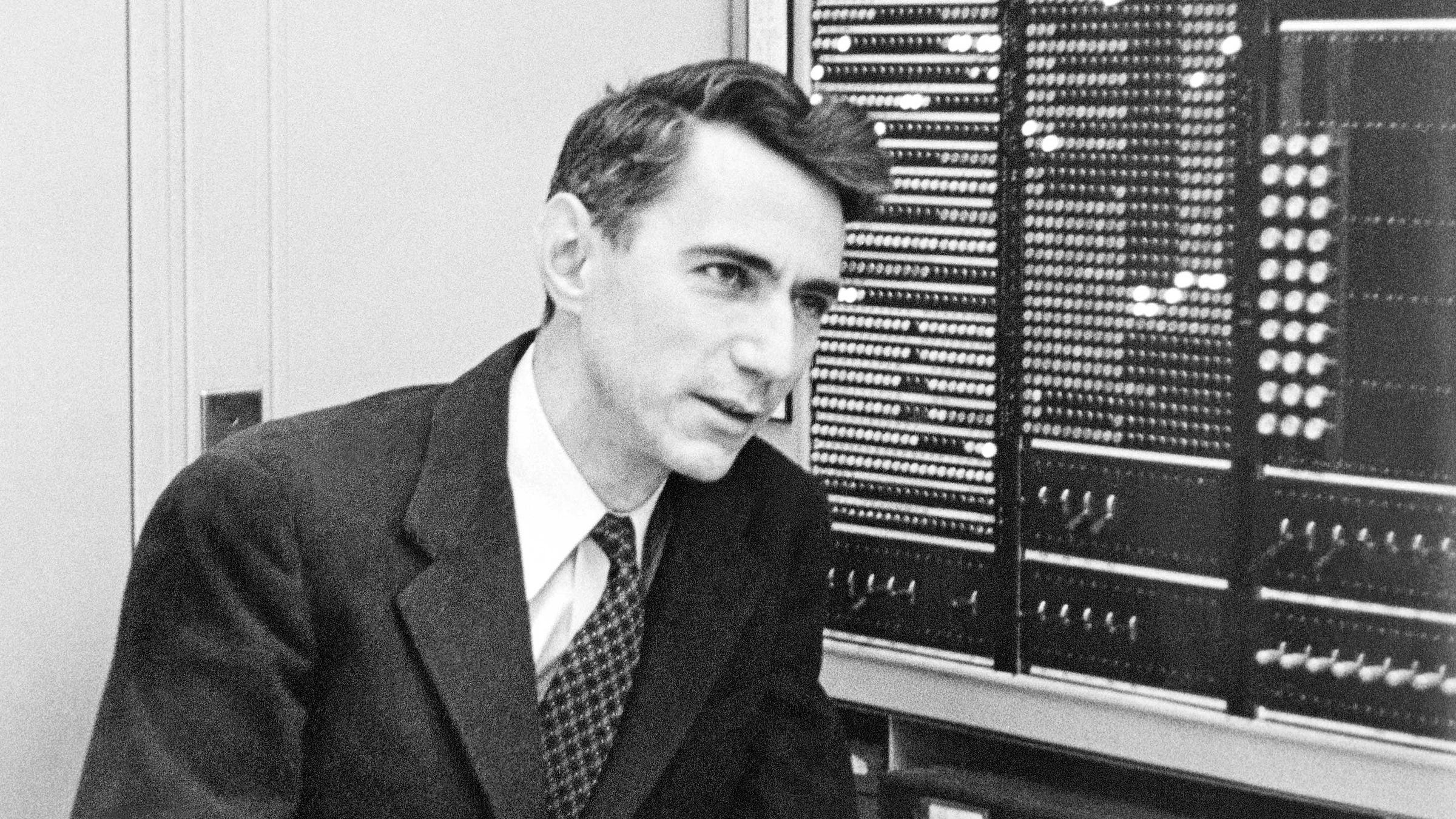 Black and white photo of Claude Shannon in front of a computer