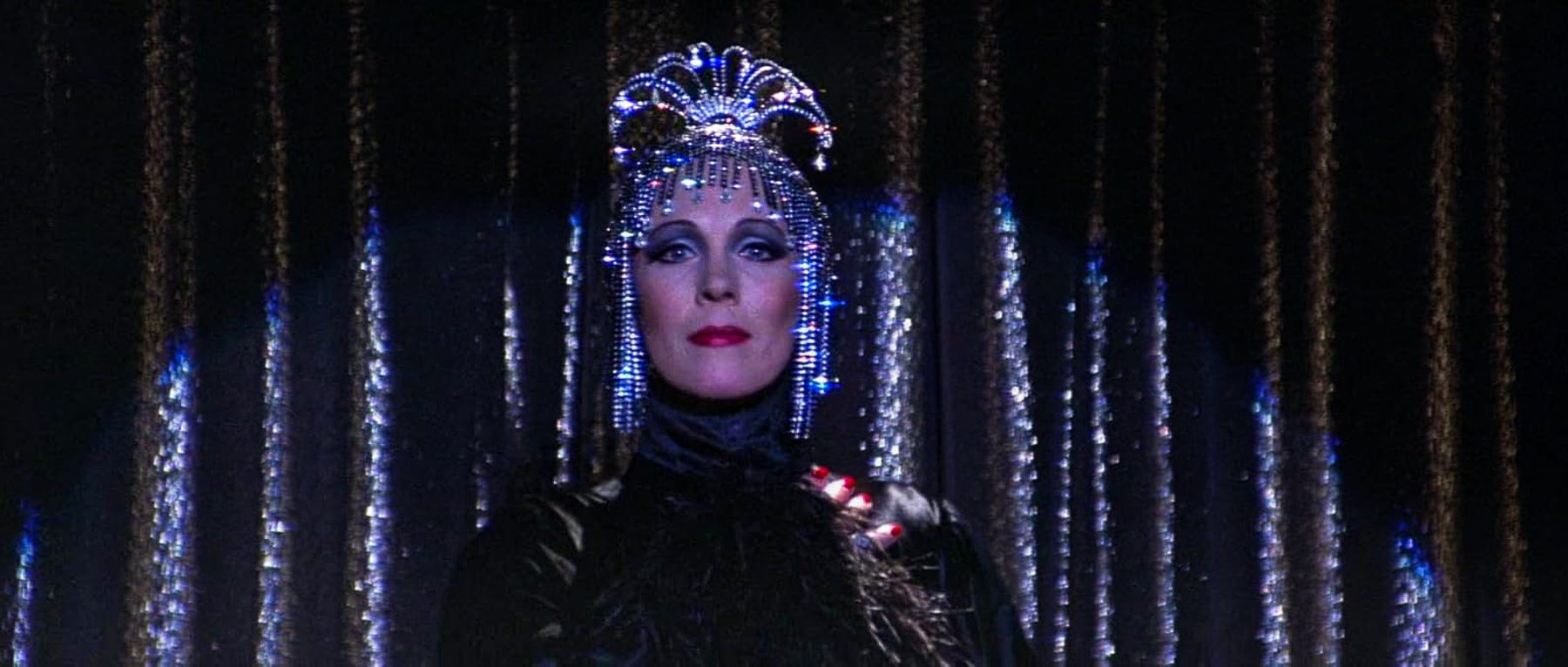 Julie Andrews takes center stage in full glam: a bedazzled turban, sequin-studded costume, and a confident, commanding stare under theatrical lighting. Julie Andrews takes center stage in full glam: a bedazzled turban, sequin-studded costume, and a confident, commanding stare under theatrical lighting.