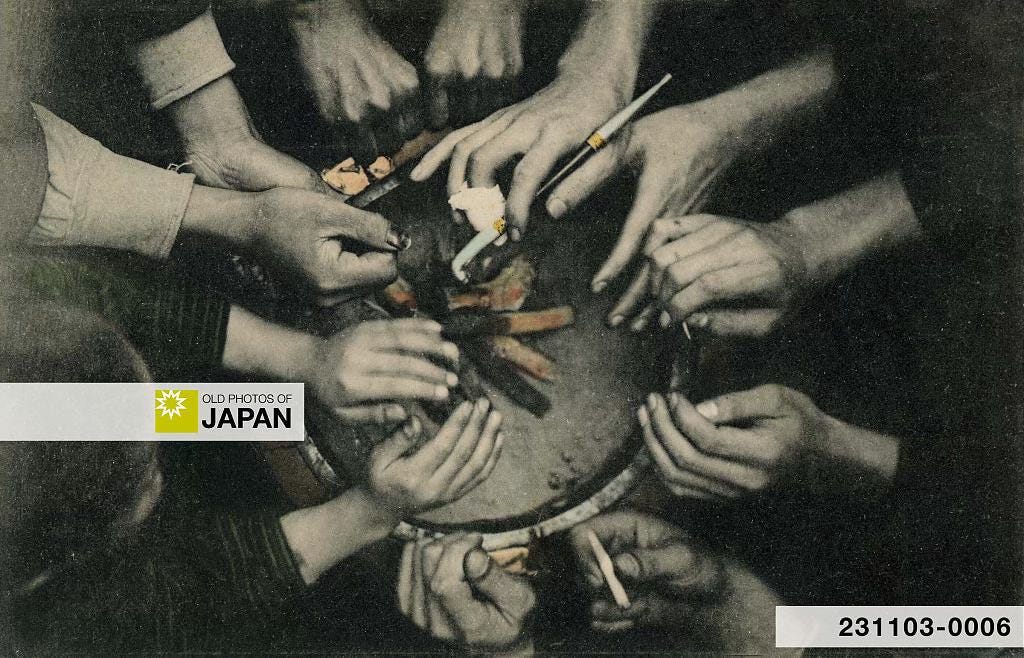 Many hands crowding a hibachi, 1900s